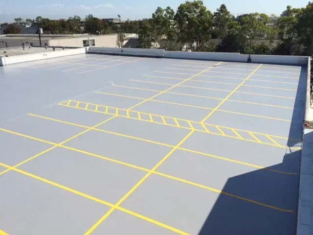 Empty rooftop parking lot with yellow painted lines and gray surface under a clear sky
