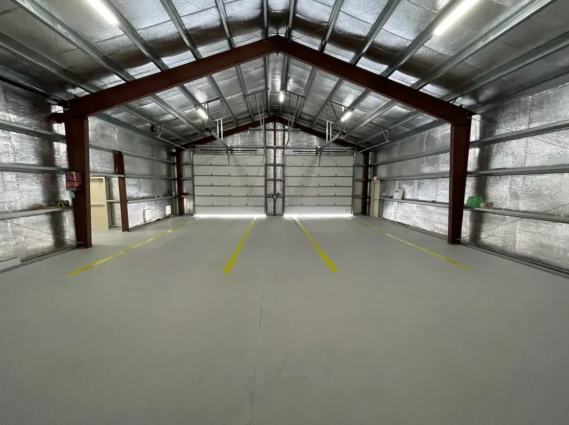Empty metal warehouse interior with a concrete floor and yellow center lines