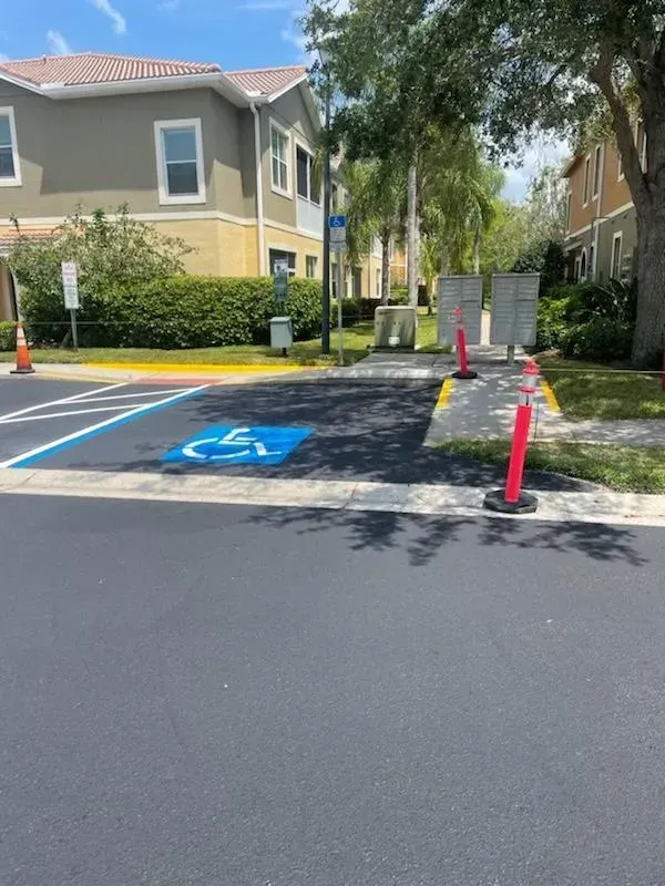 Accessible parking space with blue markings and orange cones in front of apartment buildings
