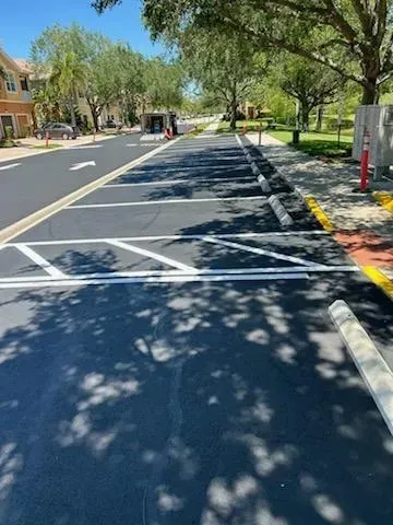 Sunny residential street with a marked bike lane, trees, parked car, and roadwork barrier ahead