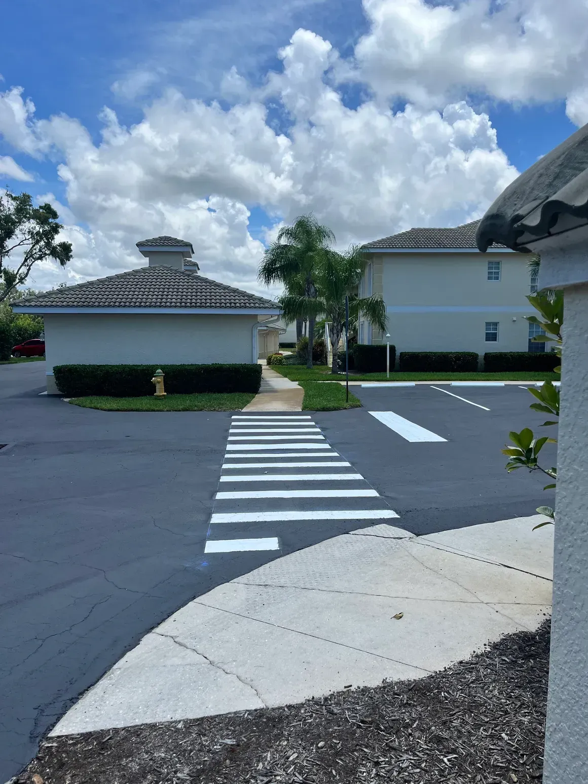 Crosswalk leading to white buildings under a blue sky with scattered clouds