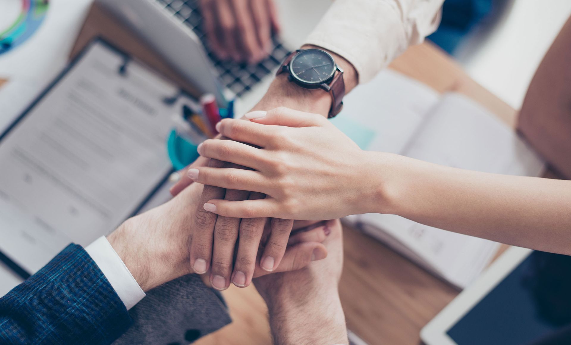 A group of people are putting their hands together.