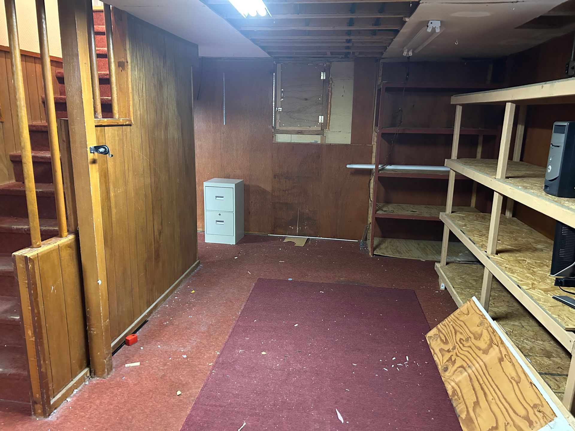 Basement storage area with stairs on the left, shelves on the right, and filing cabinet in the middle.