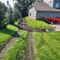 A red tractor sits on a lawn next to a house, with deep tire tracks and exposed soil running through the green grass.
