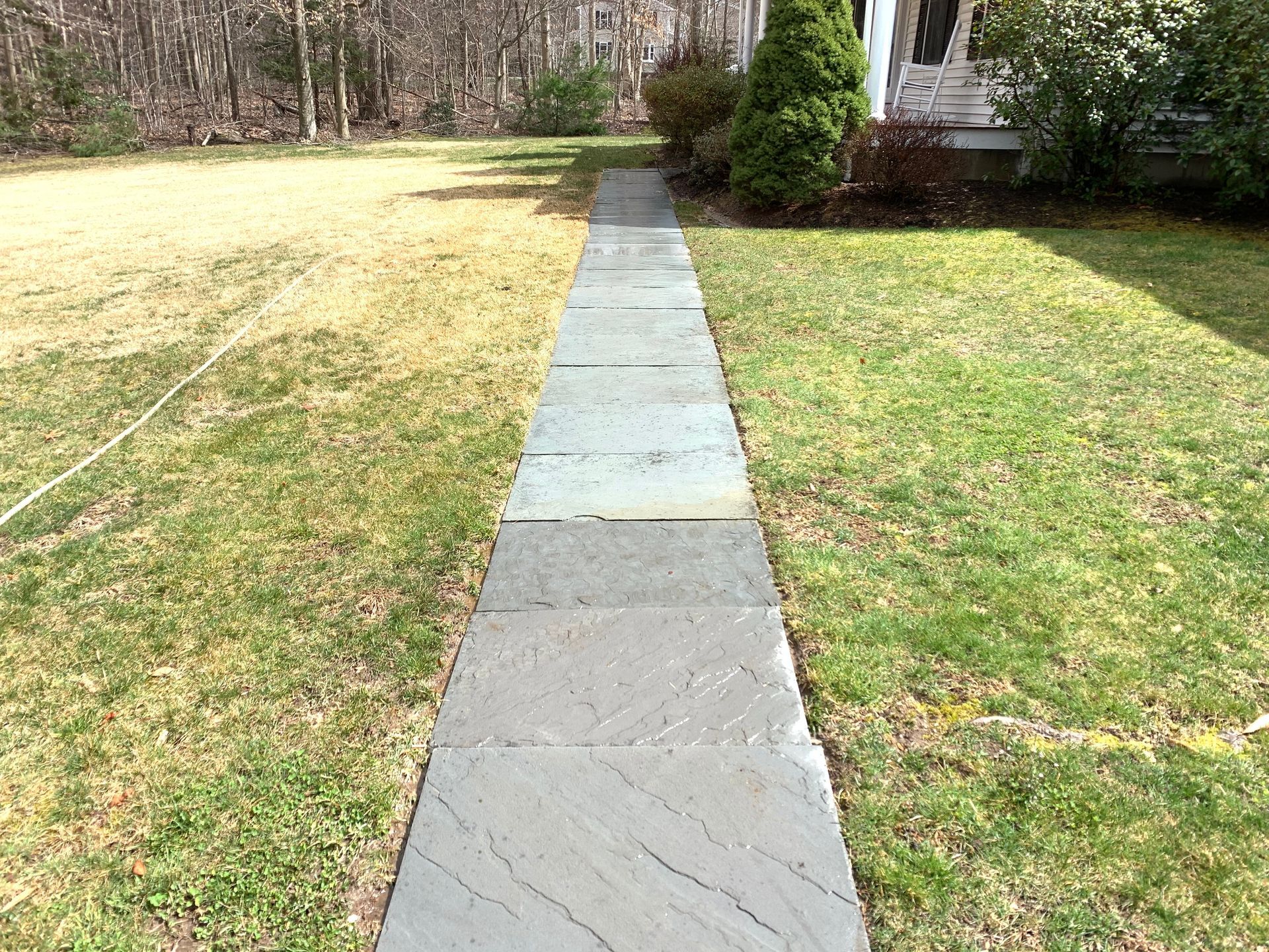A stone walkway leading to a house in a grassy yard.