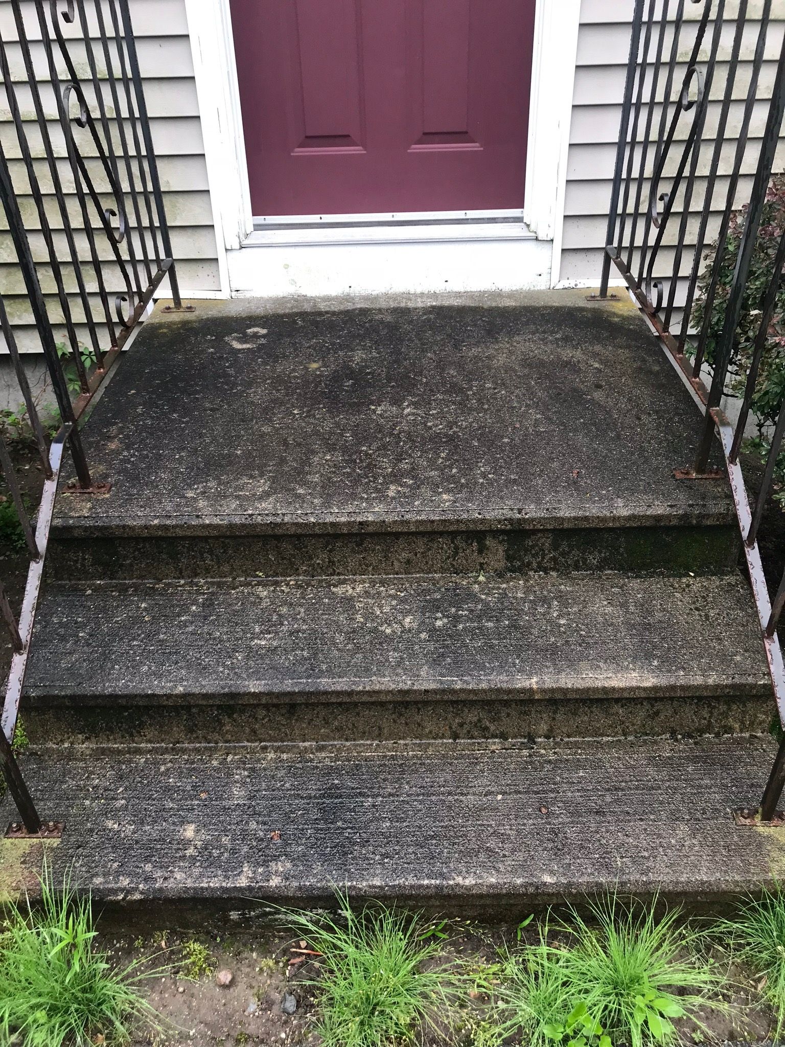 A dirty set of stairs leading up to a purple door of a house.