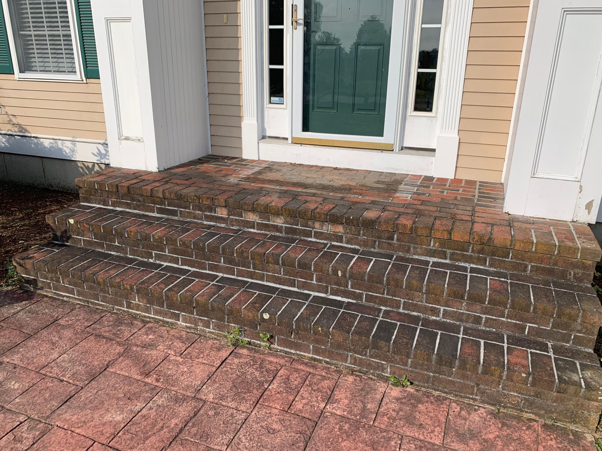 A brick porch with steps leading up to the front door of a house.