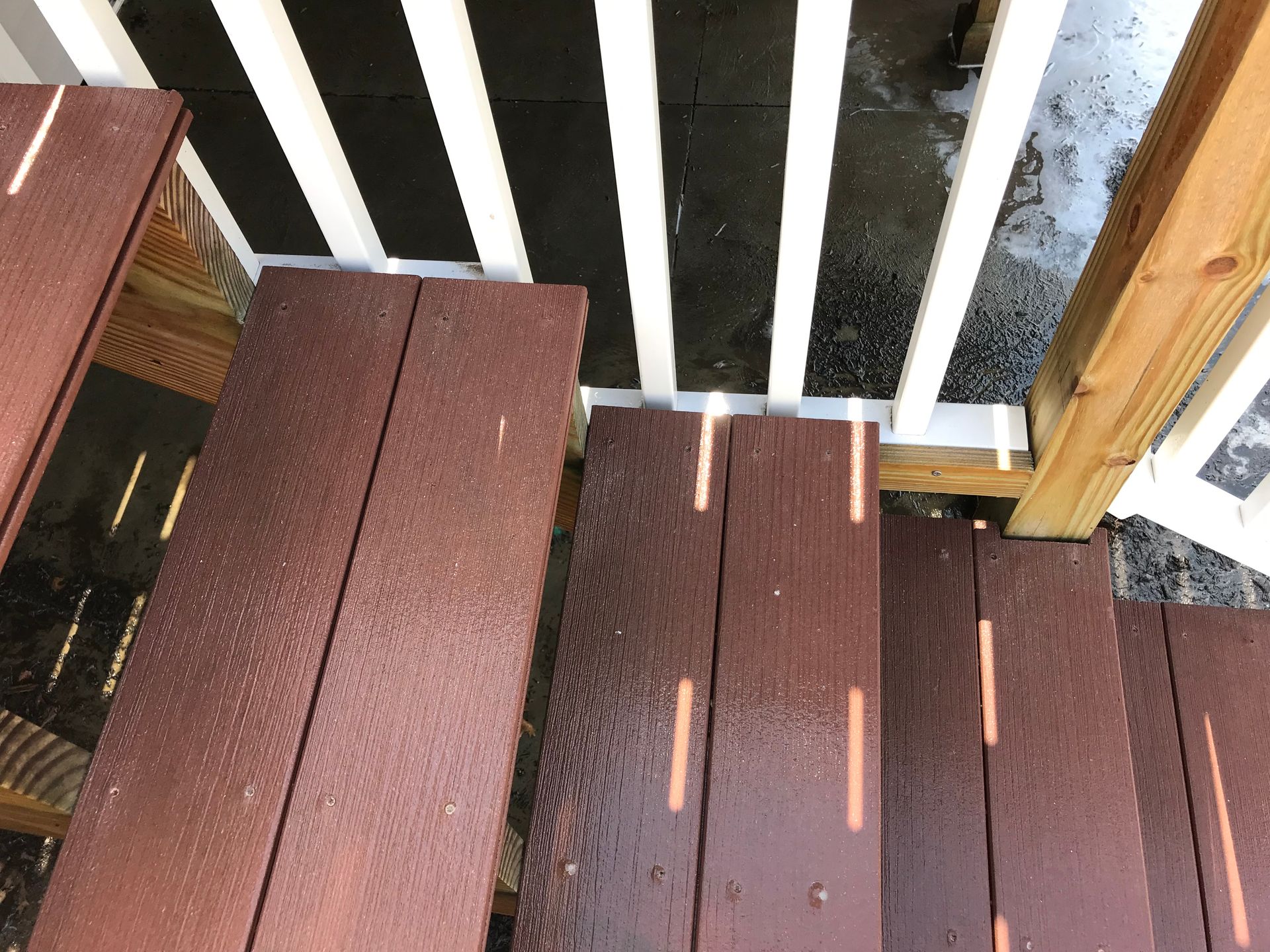 A wooden deck with stairs and a white railing