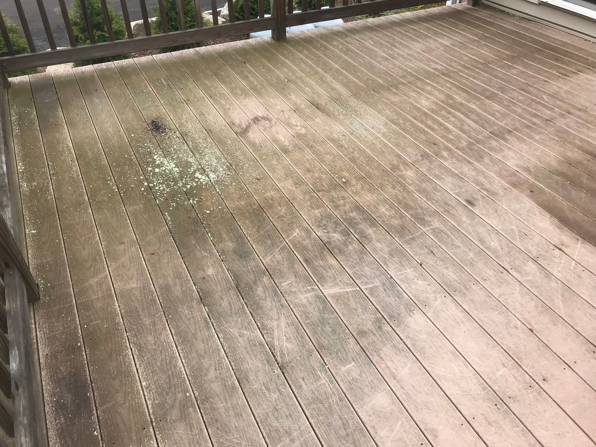 A dirty wooden deck with a railing in the background.