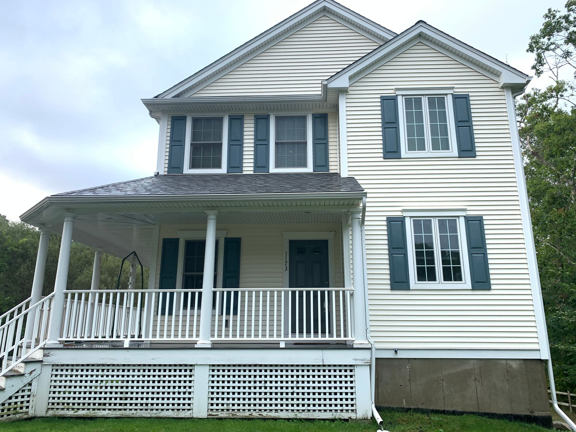 A white house with blue shutters and a large porch