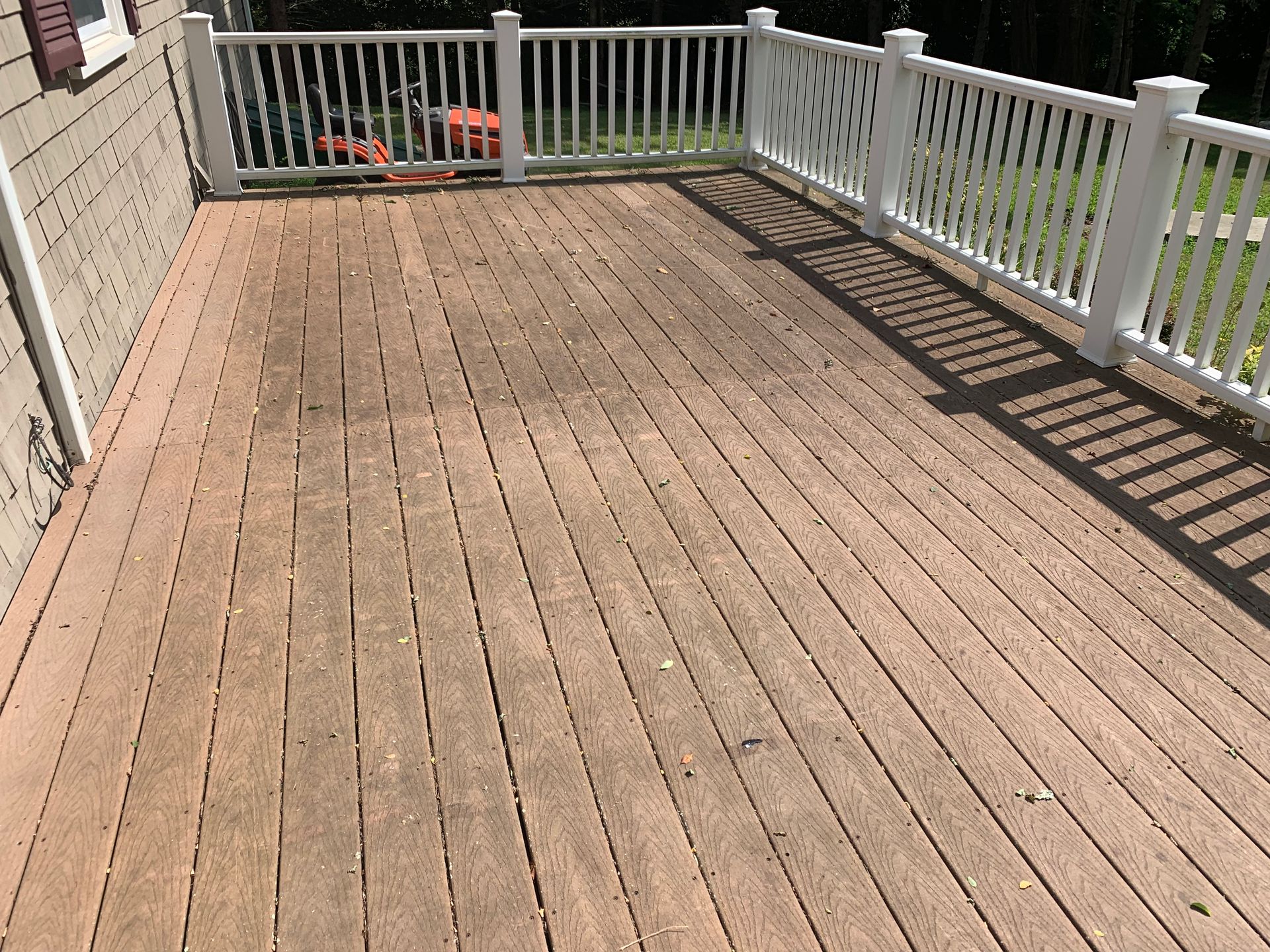 A wooden deck with a white railing and a white fence.