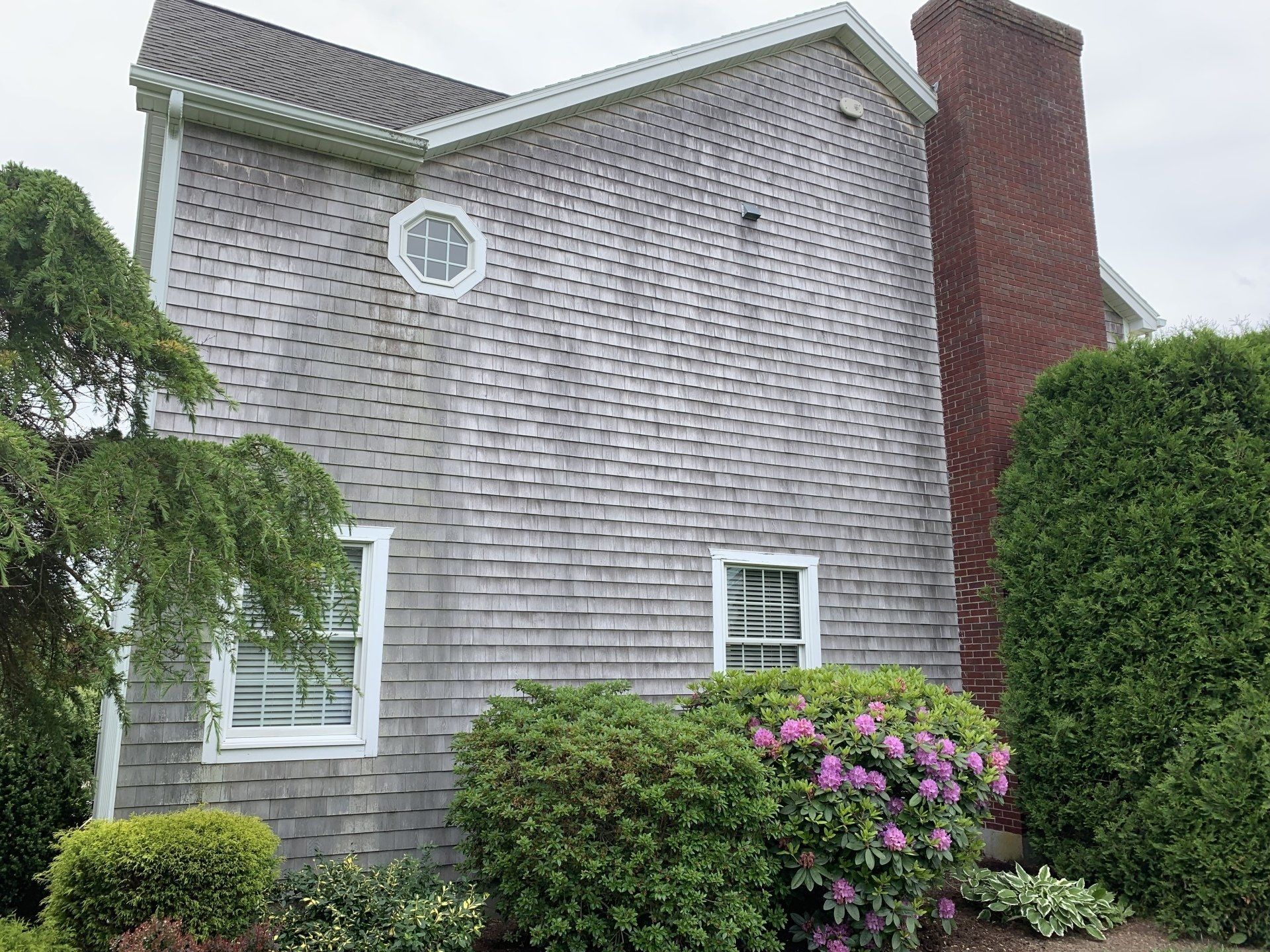 A large house with a chimney and a clock on the side of it.