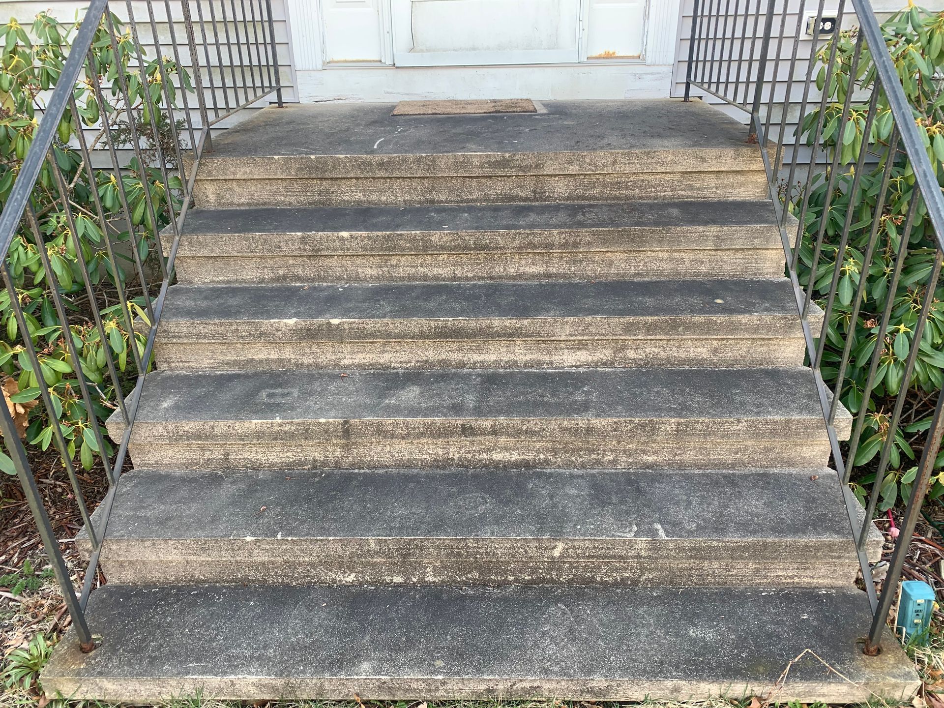 A set of stairs leading up to a house with a metal railing.