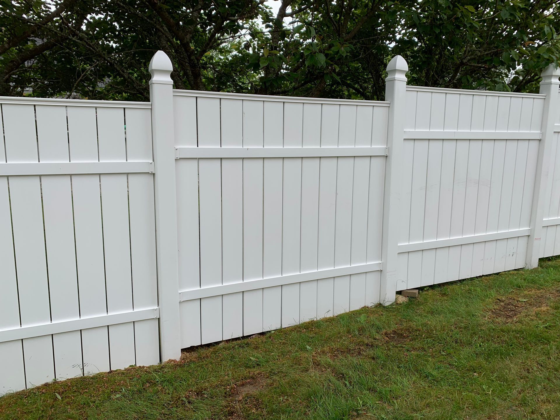 A white fence is sitting in the middle of a lush green field.
