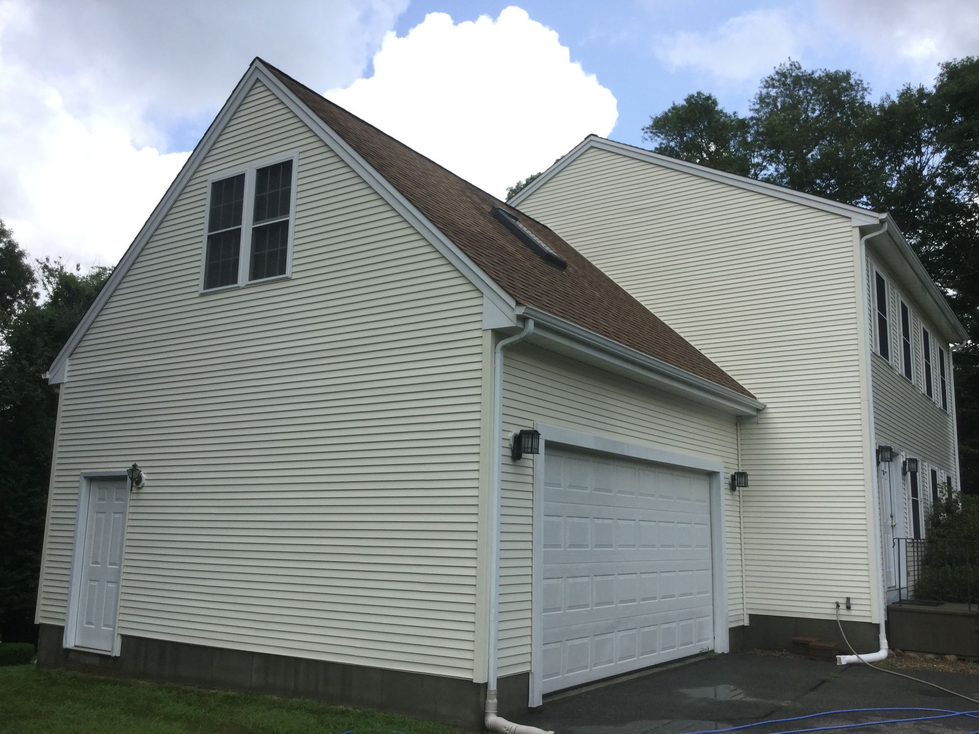 A white house with two garage doors and a brown roof