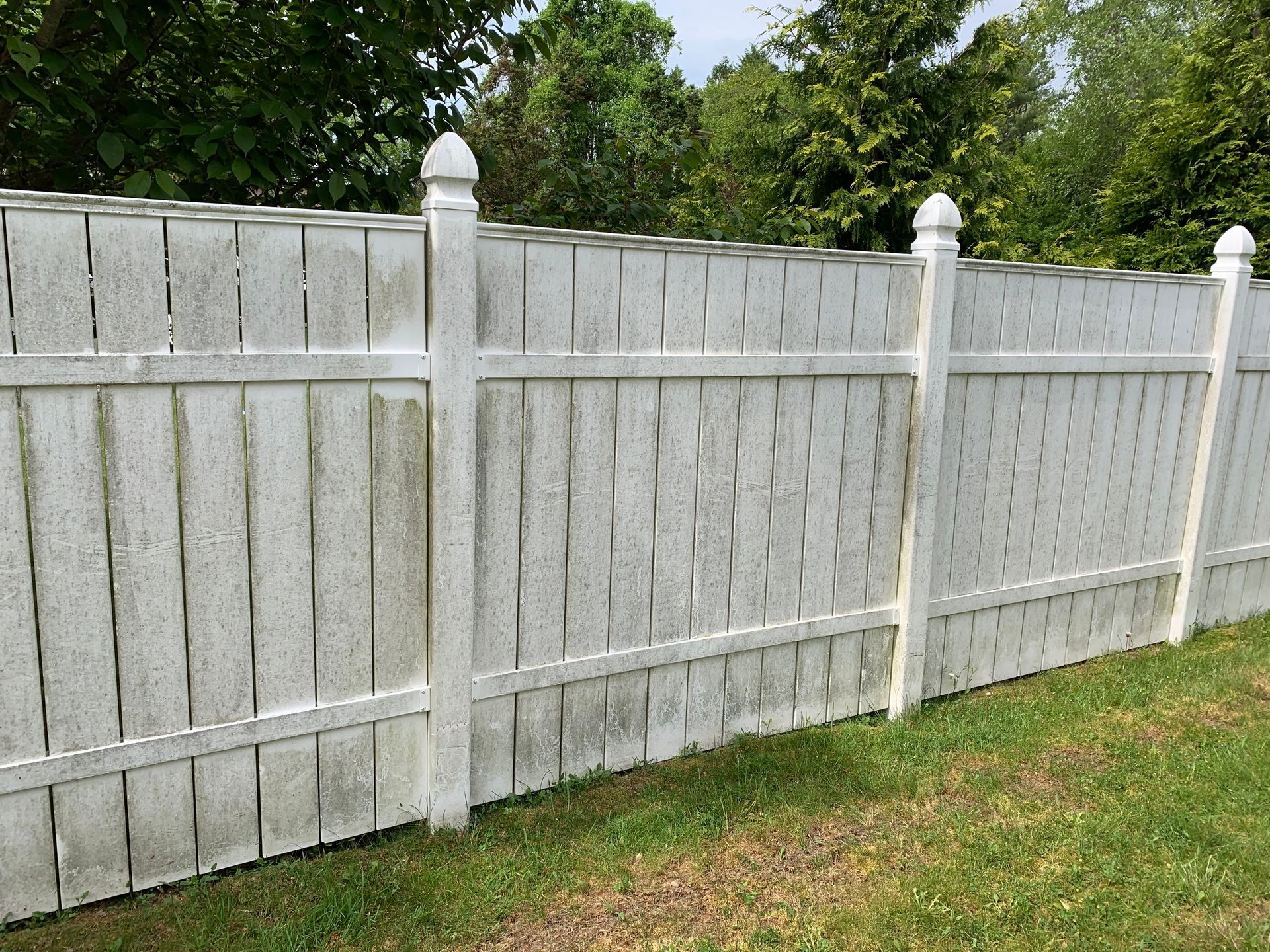 A white fence is sitting on top of a lush green field.