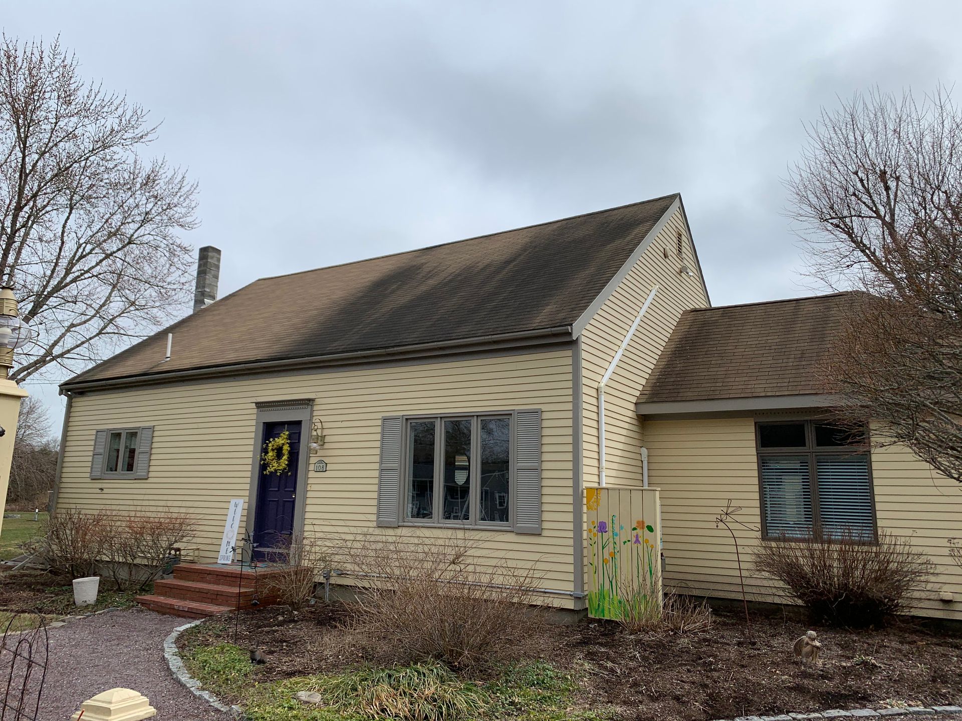 A small yellow house with a brown roof and a blue door.