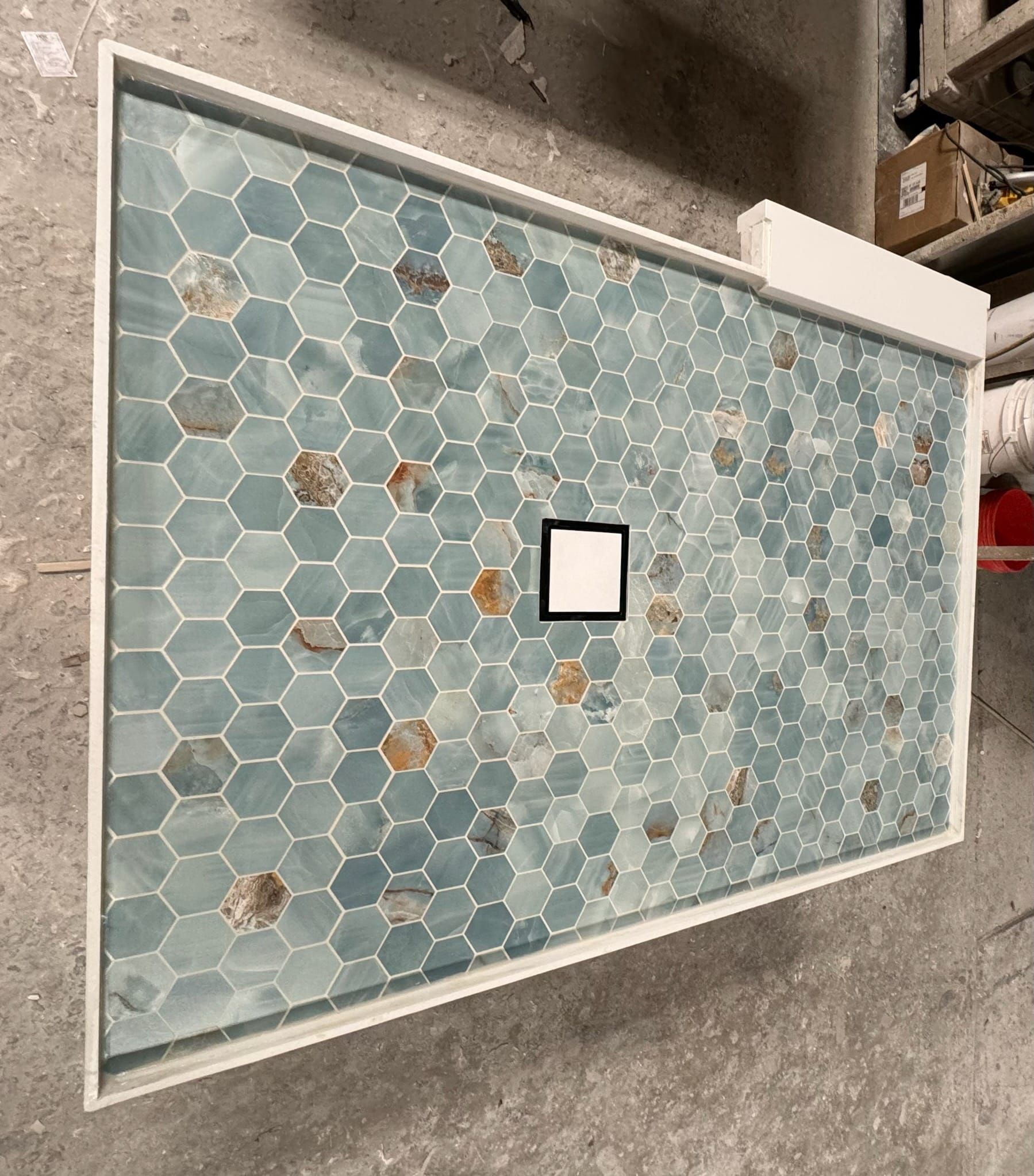 A shower stall with a blue tile floor and a white frame.