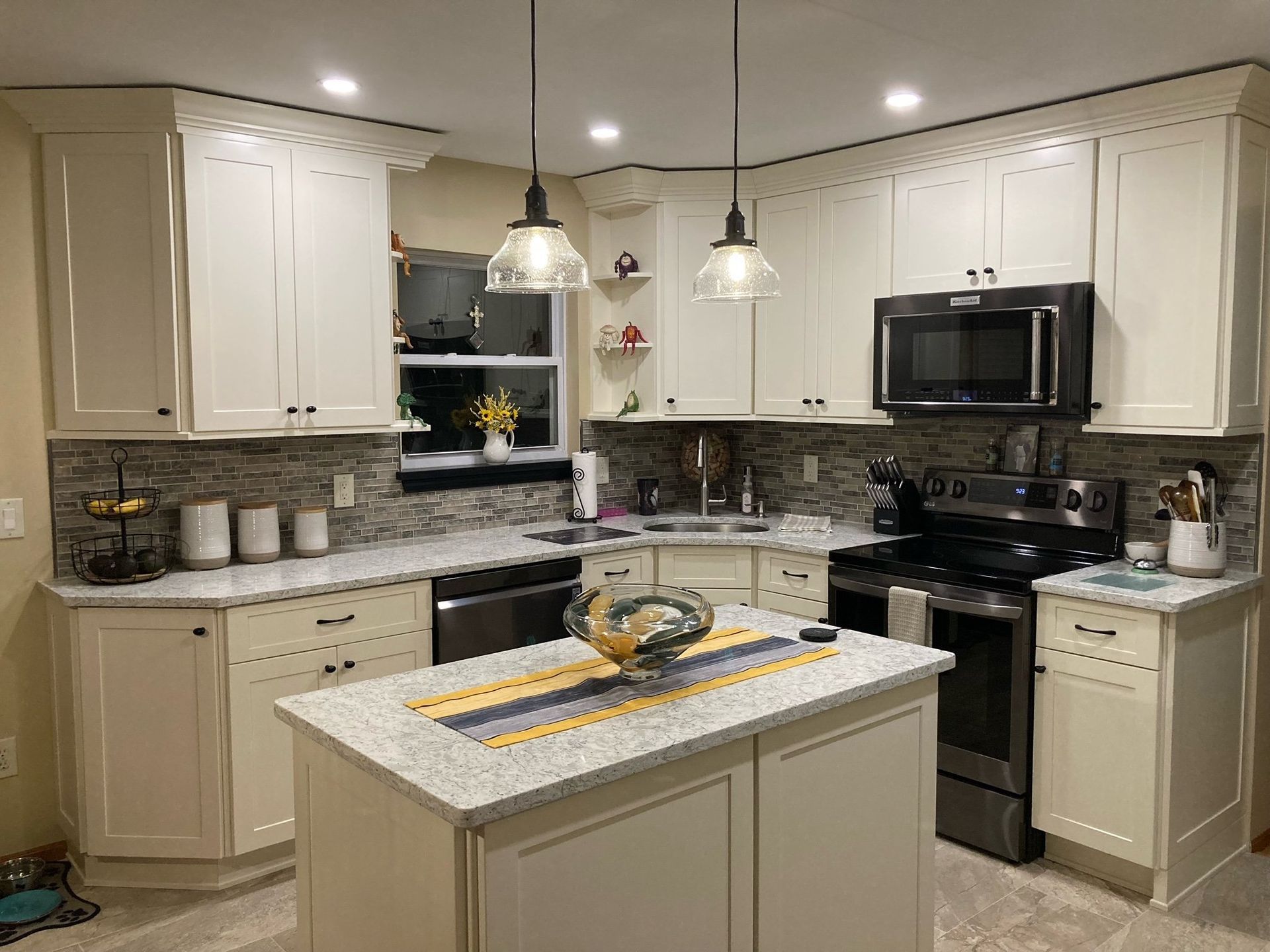A kitchen with white cabinets , granite counter tops , stainless steel appliances and a large island.