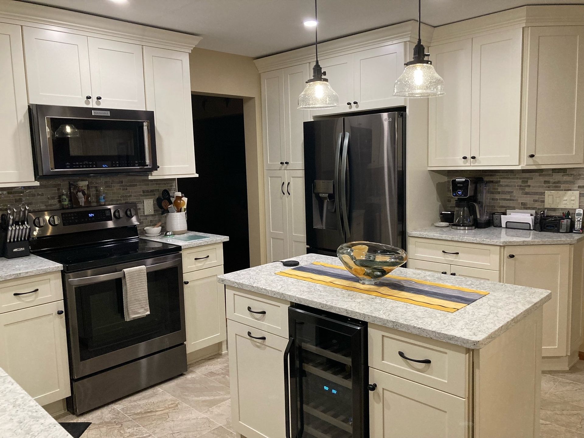 A kitchen with white cabinets , stainless steel appliances , and a large island.