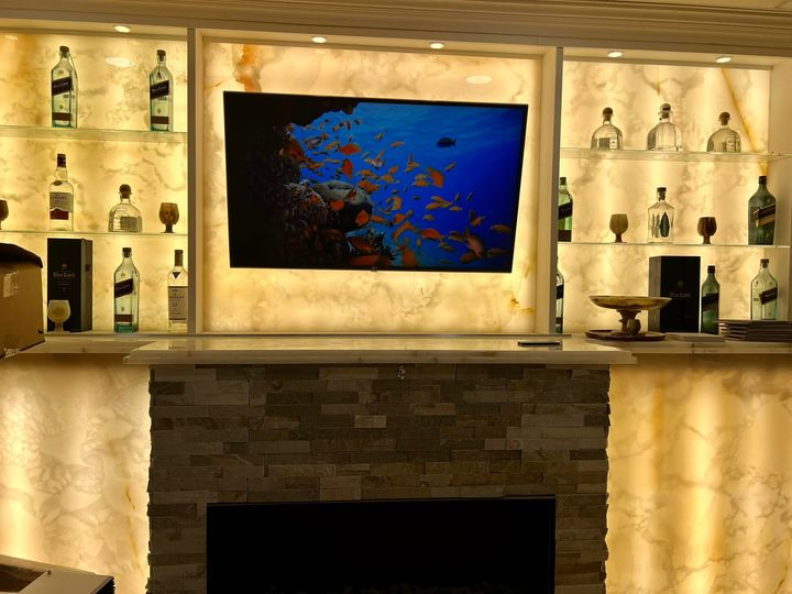 A bar with bottles of alcohol and a television on the wall.