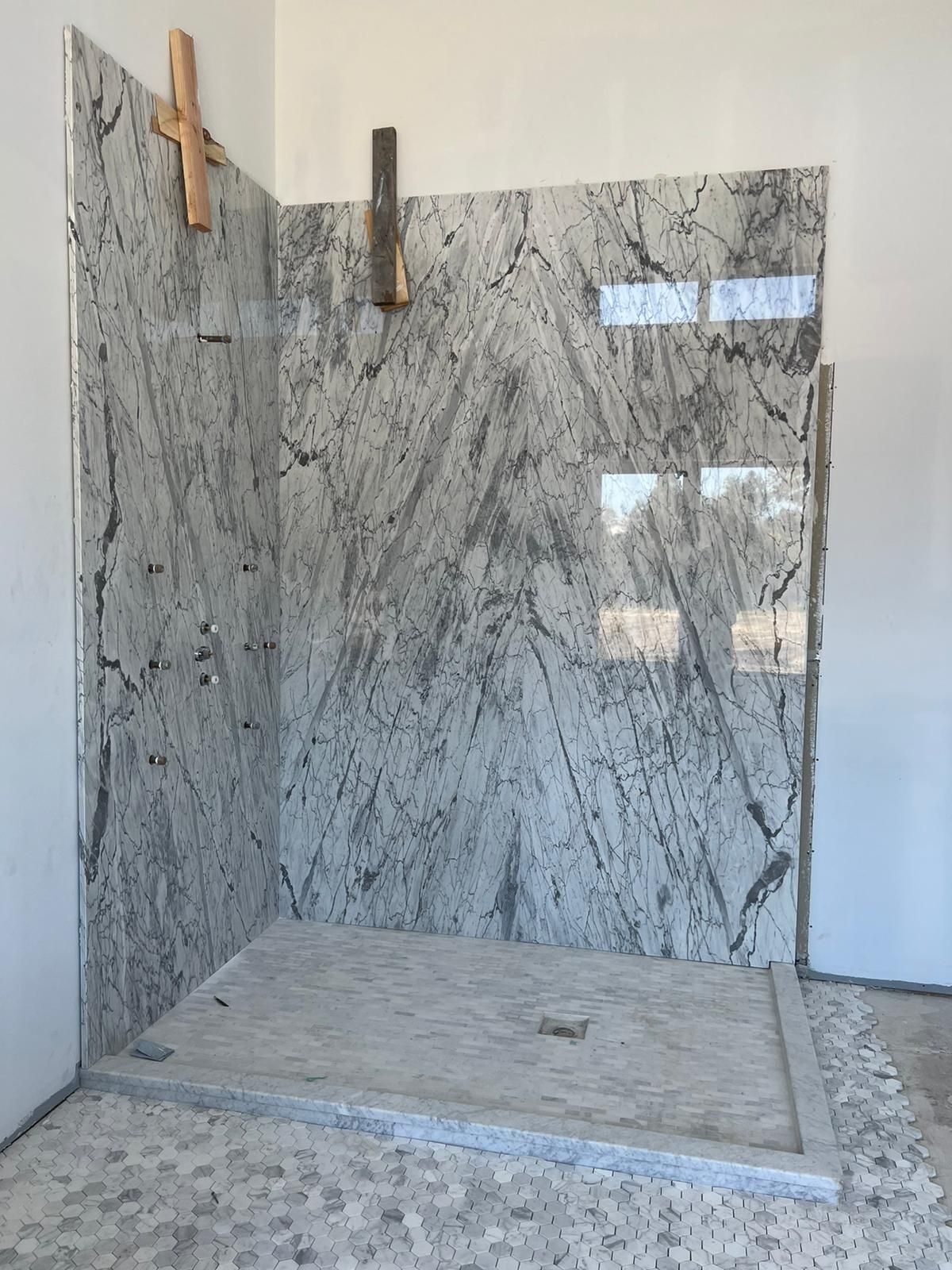 A bathroom with a walk in shower surrounded by marble tiles.