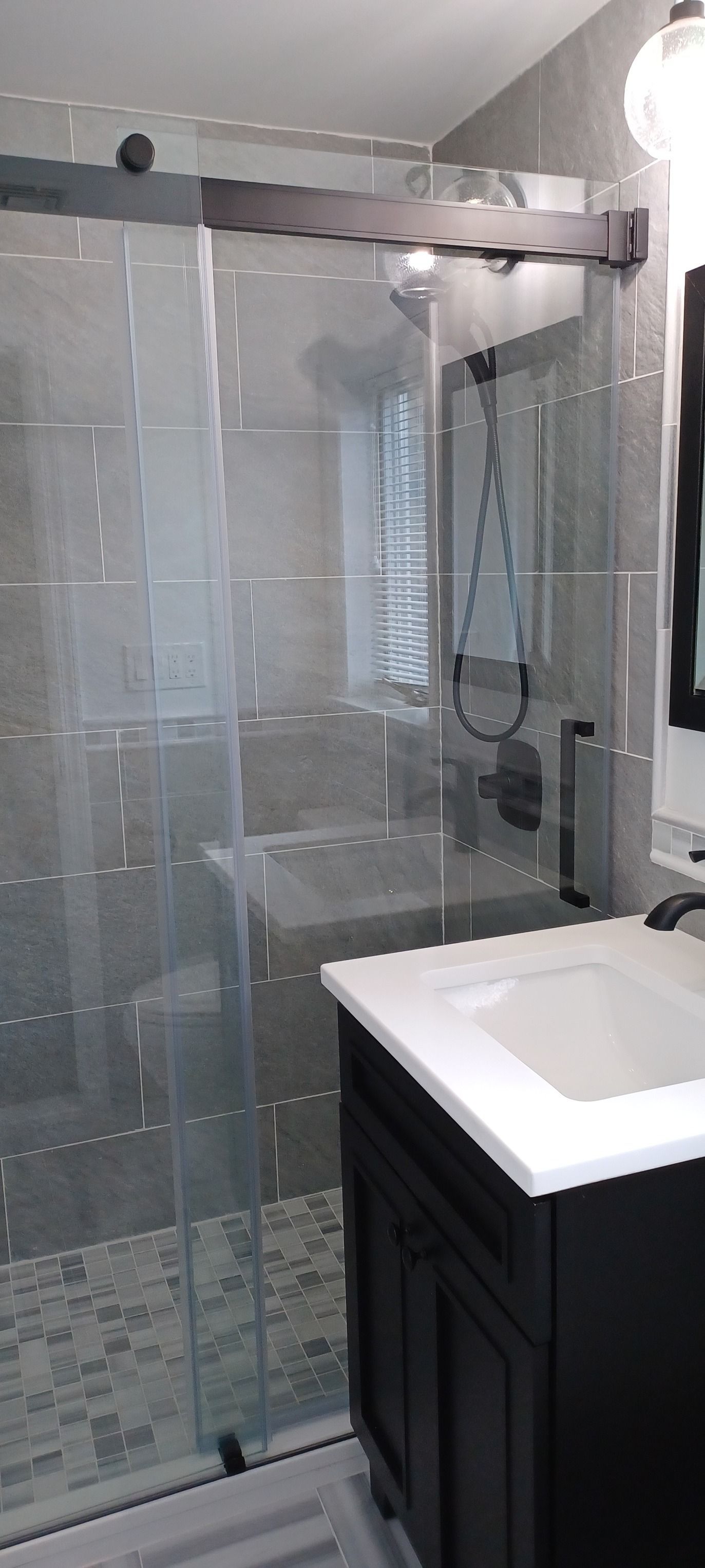 A bathroom with a sink and a shower with a sliding glass door.
