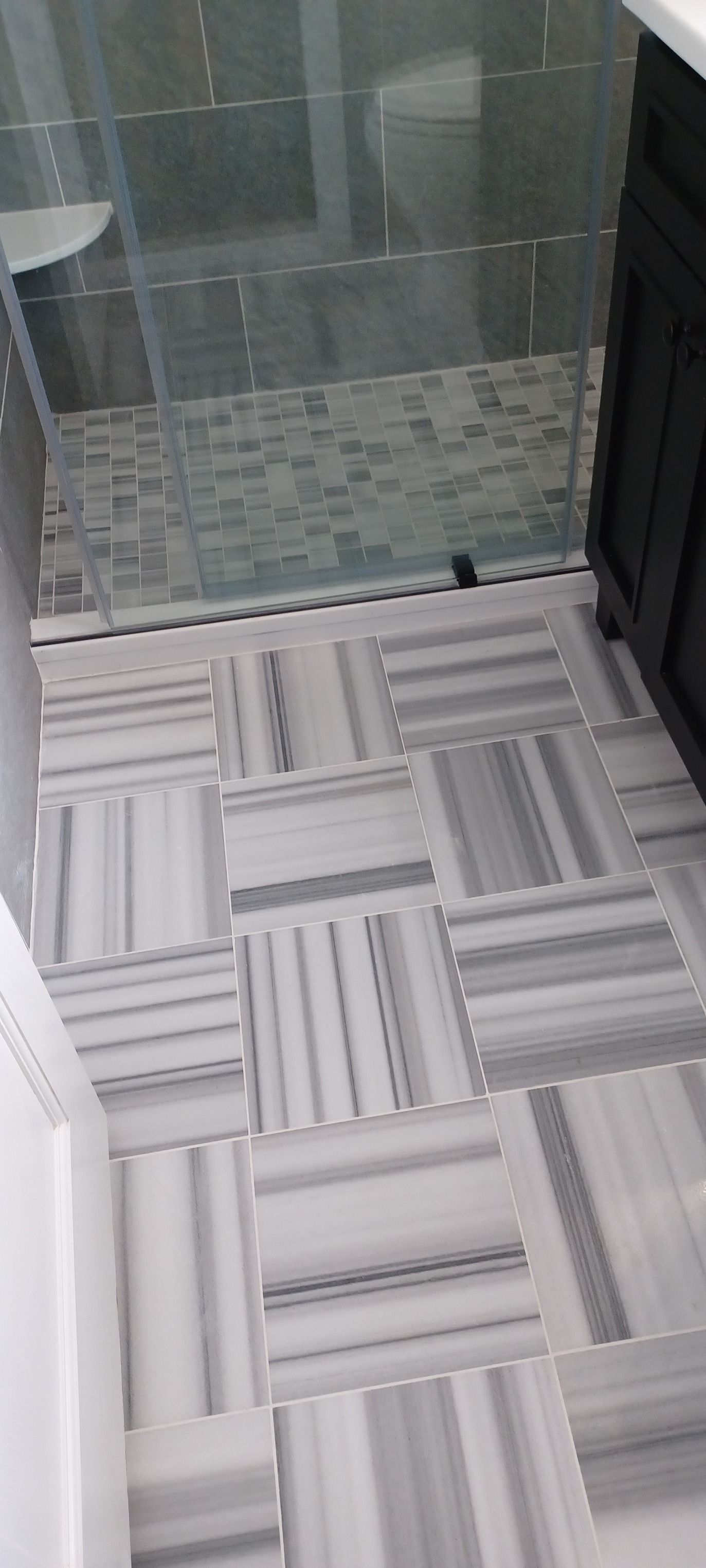 A bathroom with a tiled floor and a walk in shower.