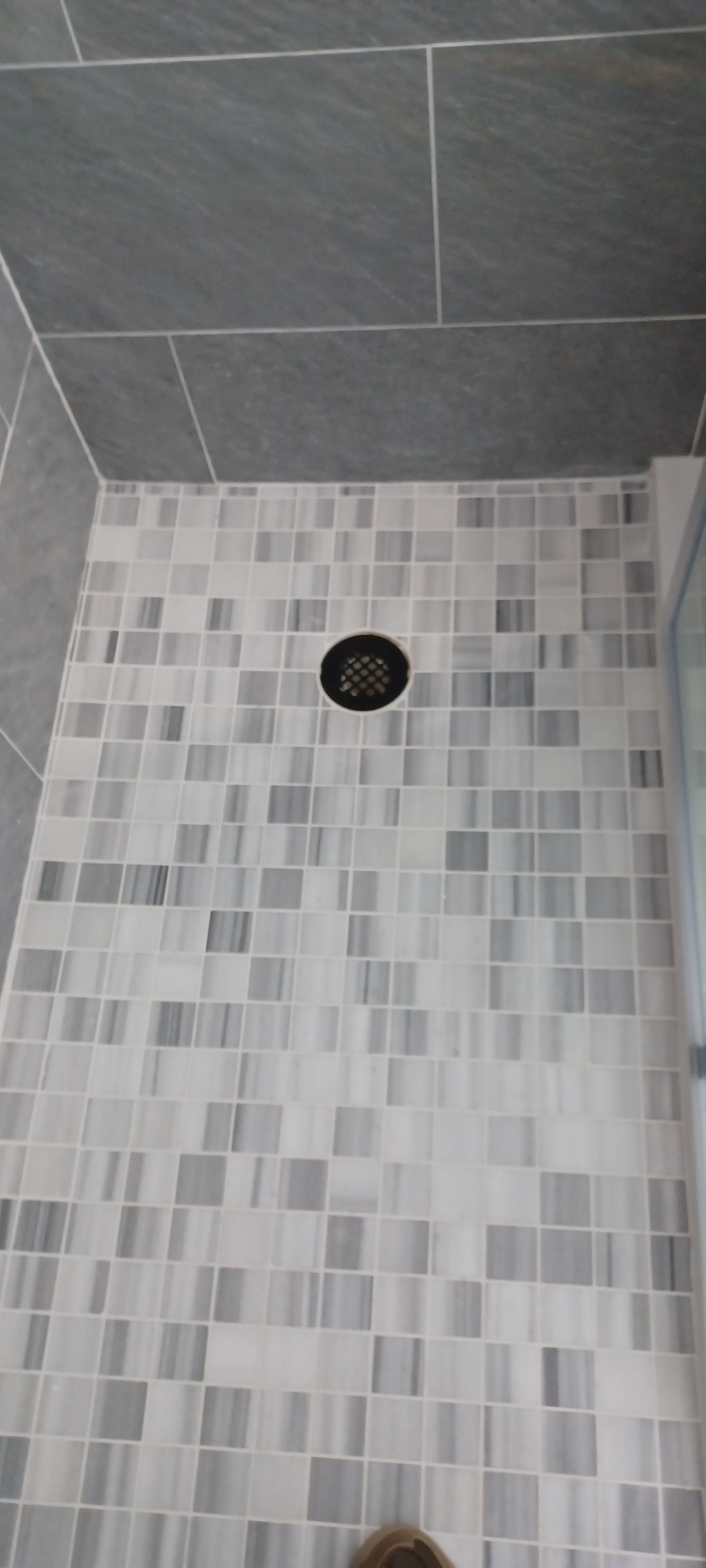 A close up of a tiled shower floor with a drain.