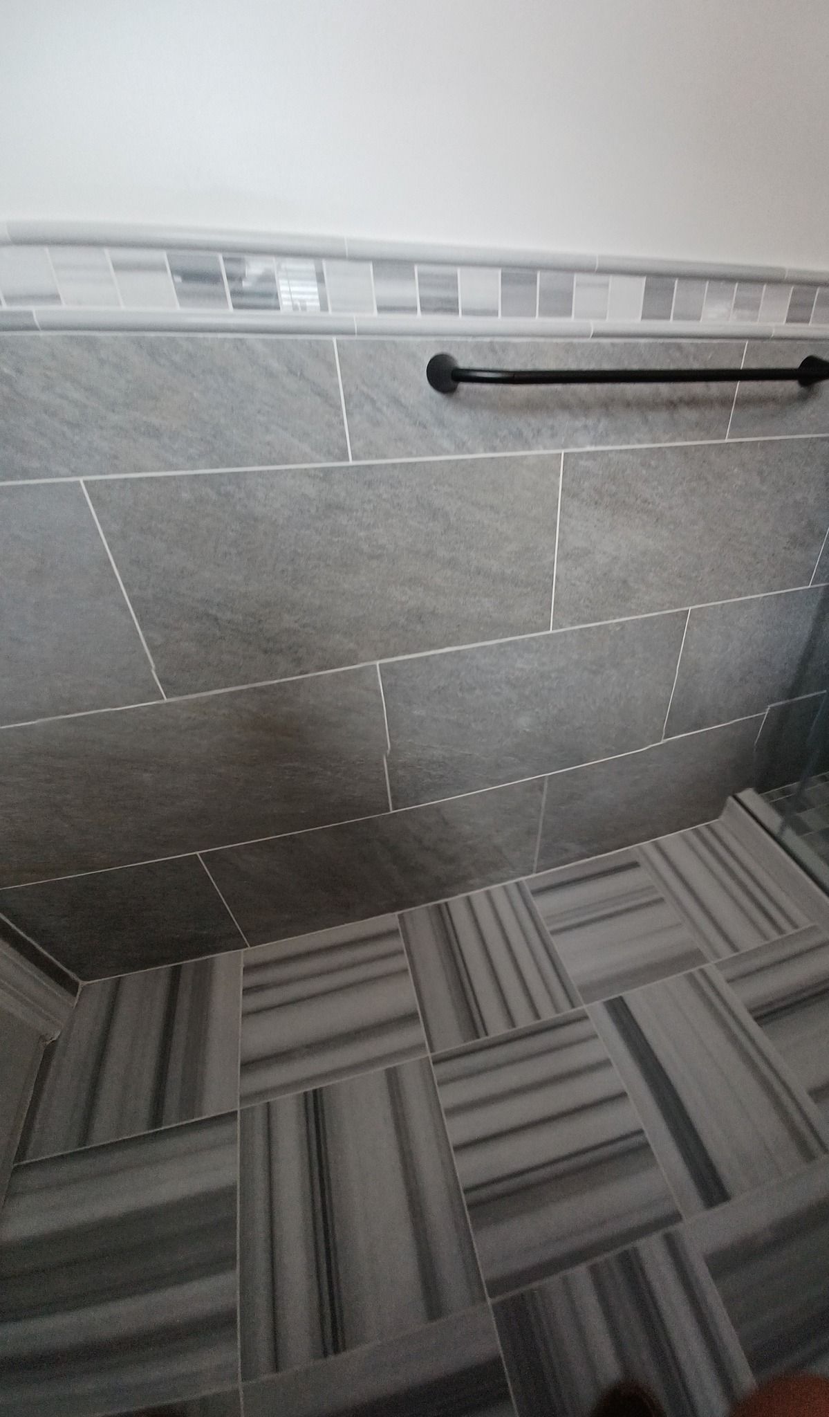 A bathroom with a tiled floor and a towel rack on the wall.