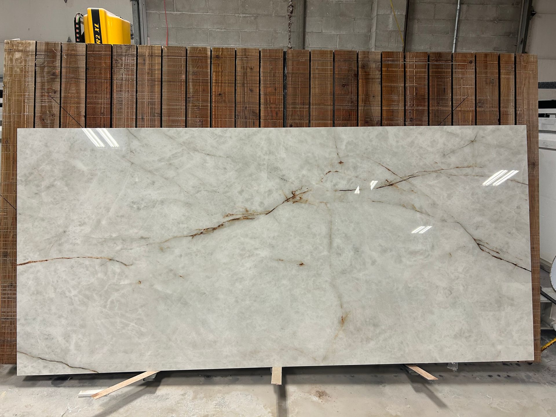 A large slab of white marble is sitting in front of a wooden fence.