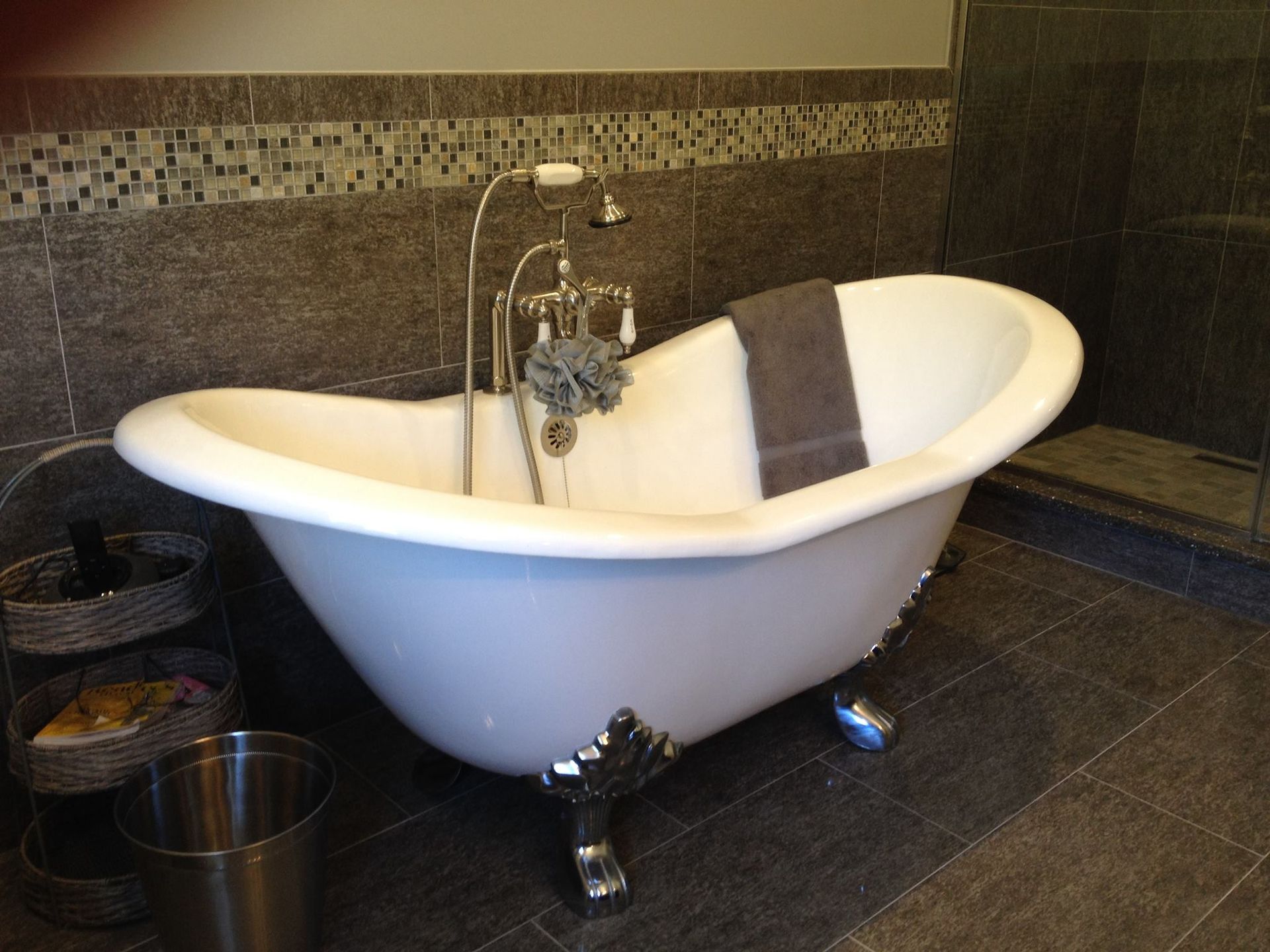 A claw foot bathtub in a bathroom next to a bucket