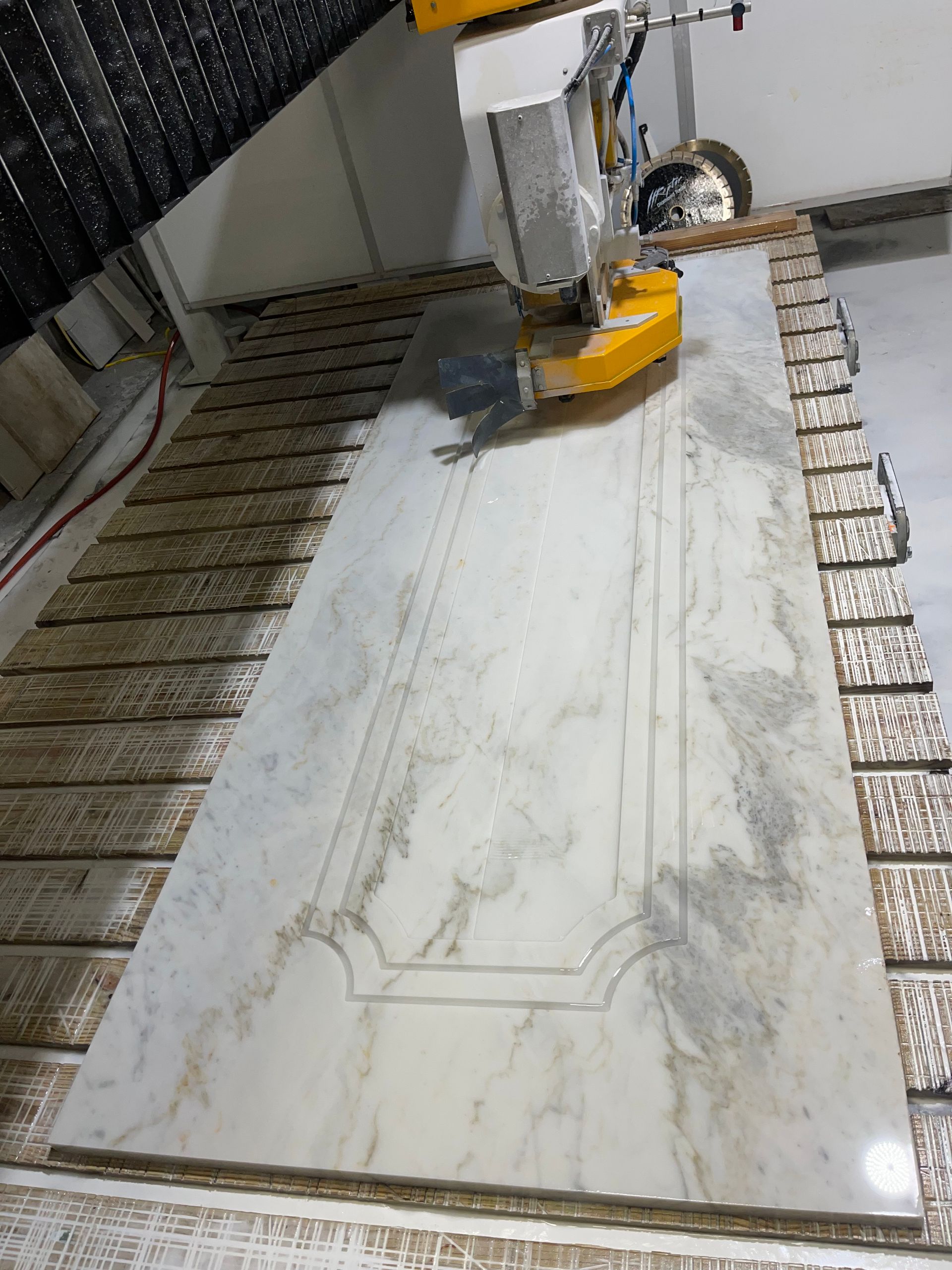 A machine is cutting a piece of marble on a table.