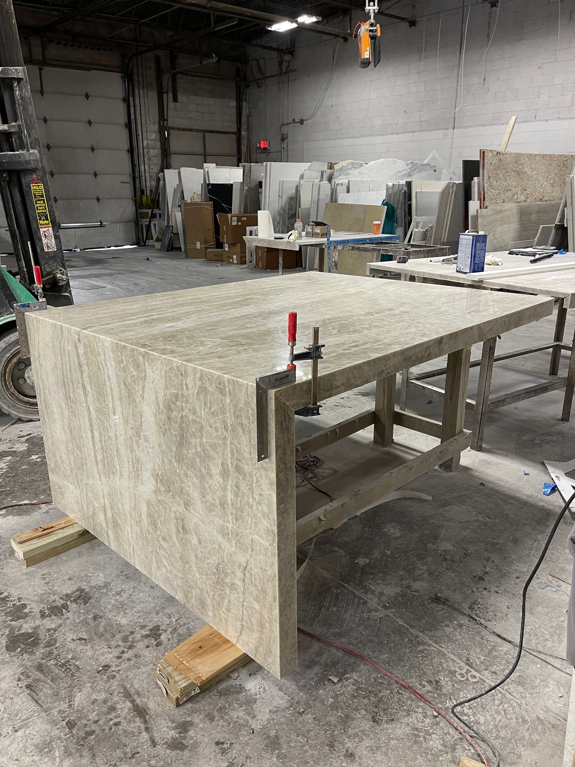 A large piece of wood is sitting on top of a wooden table in a warehouse.