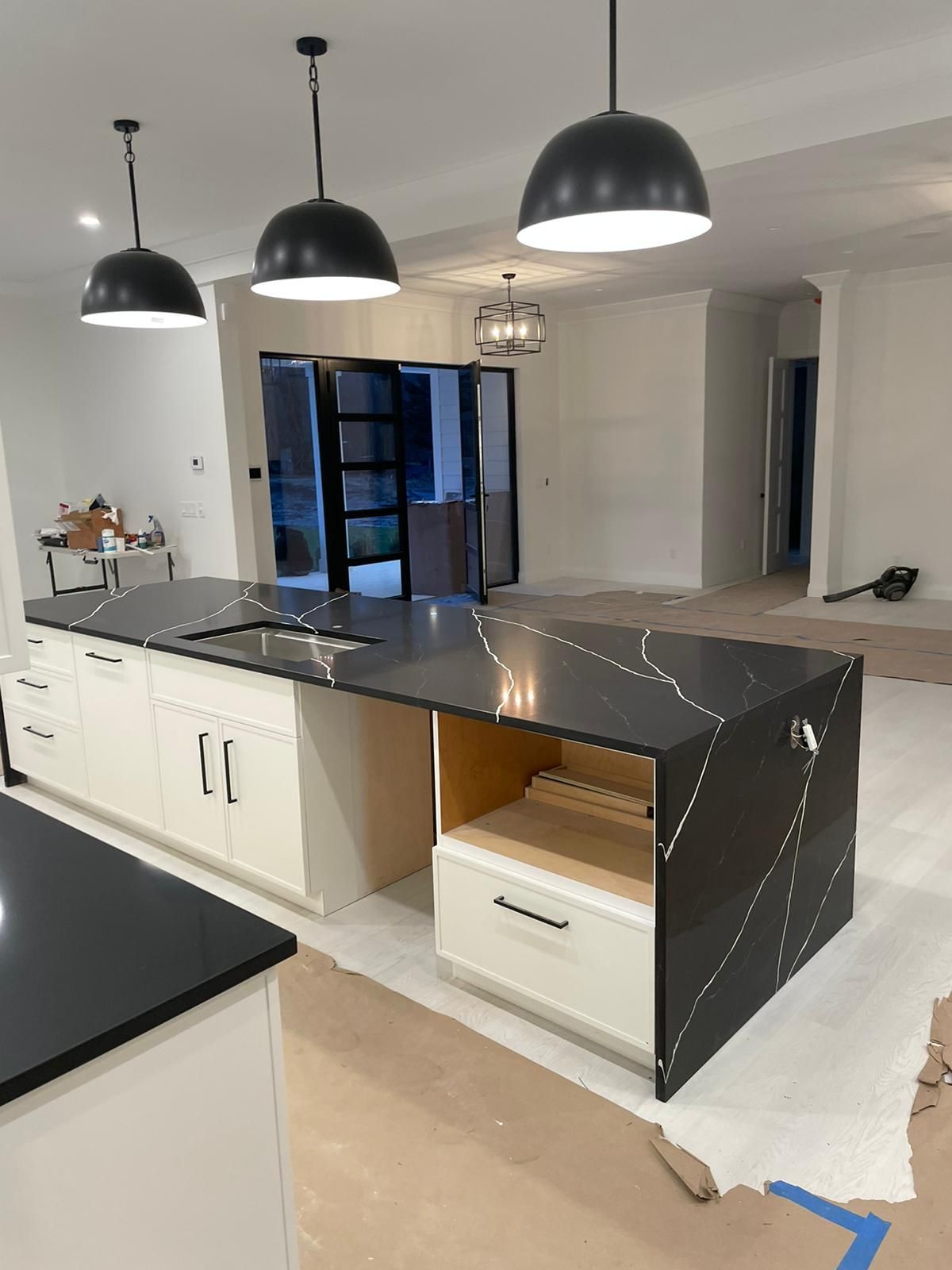 A kitchen with black counter tops and white cabinets is being remodeled.