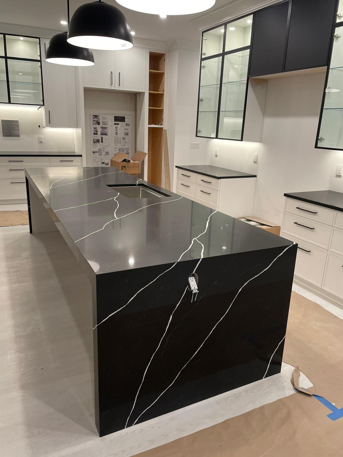 A kitchen with a large black counter top and white cabinets.