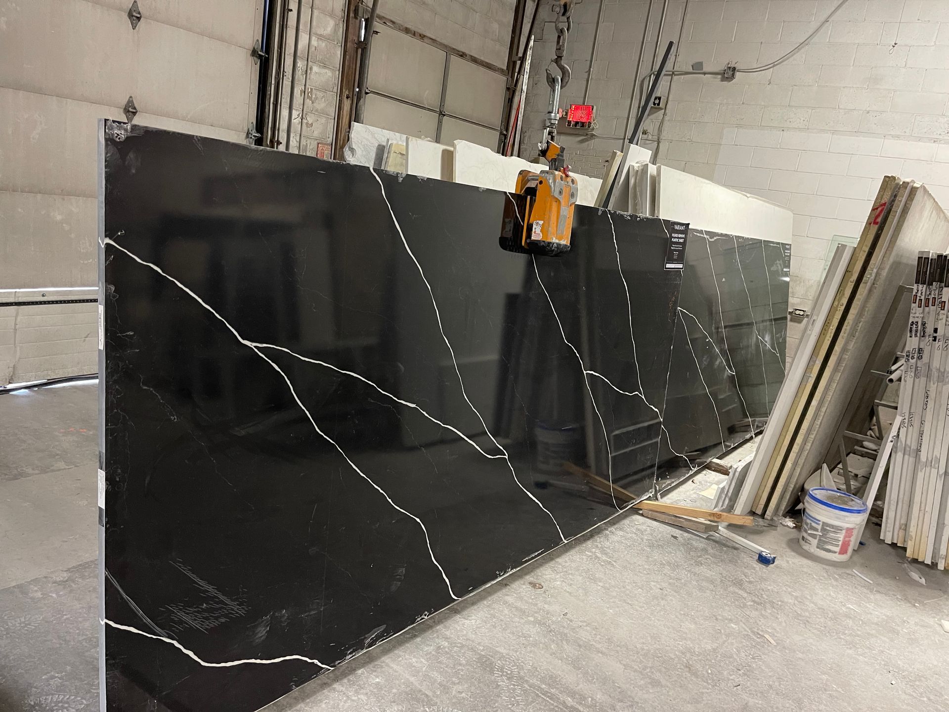 A large black granite slab is being lifted by a crane.