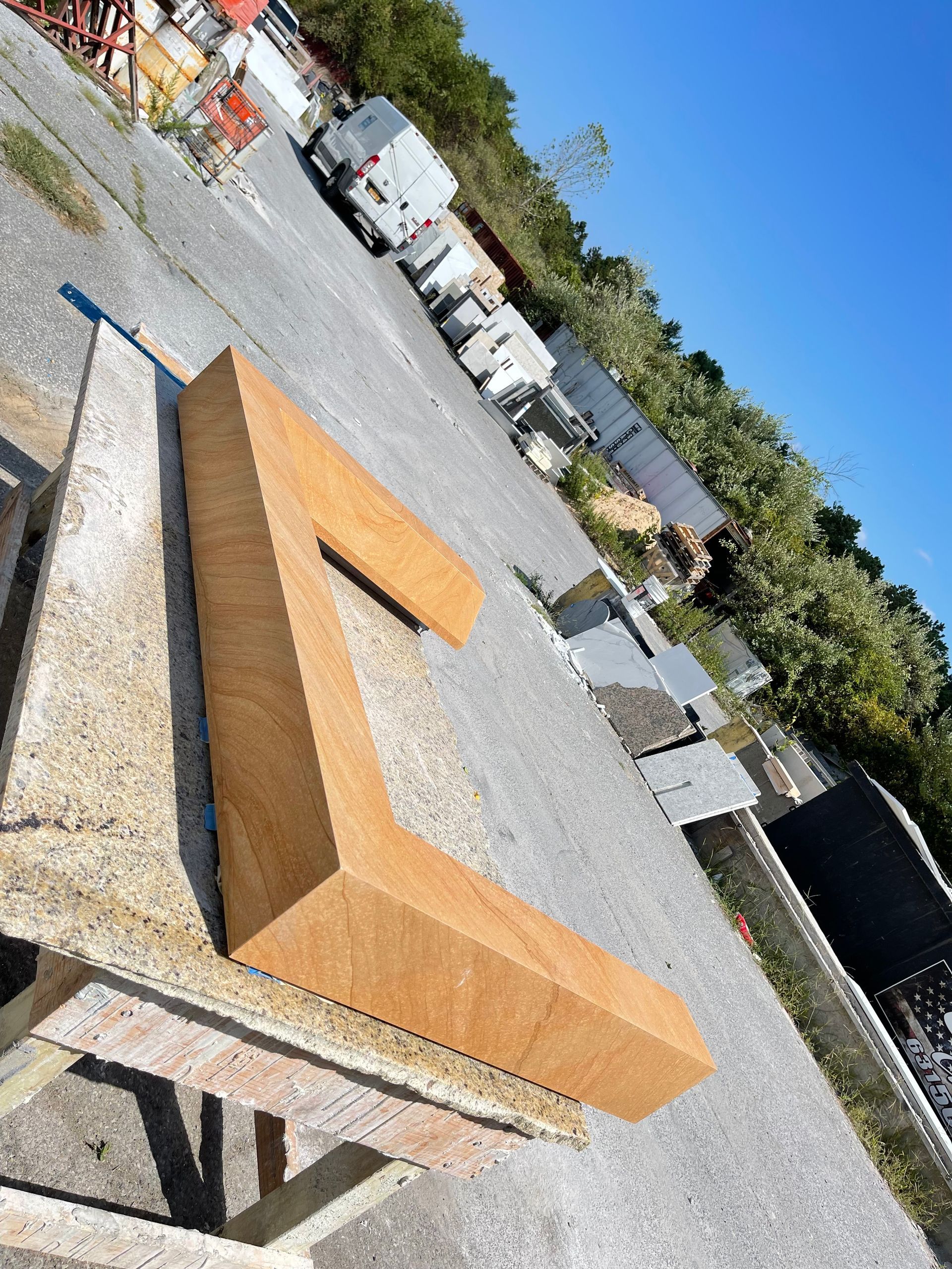 A large wooden letter a is sitting on the ground in a parking lot.