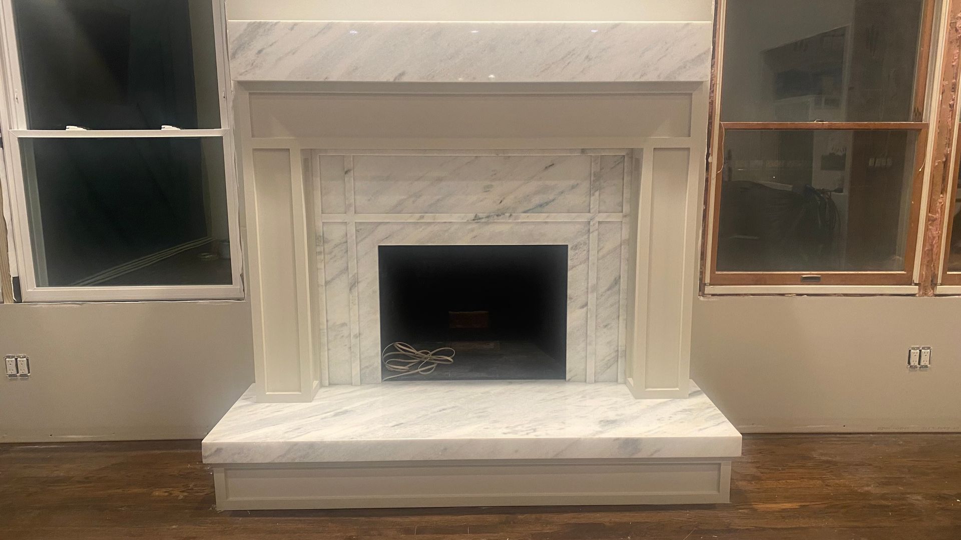 A living room with a fireplace and two windows.