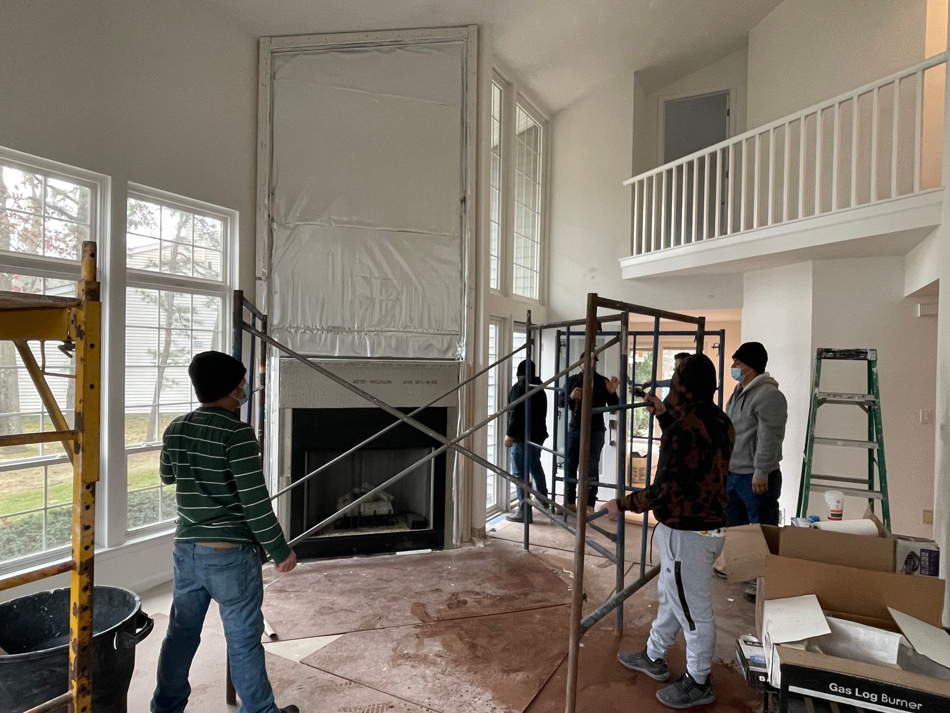 A group of people are working on a fireplace in a living room.