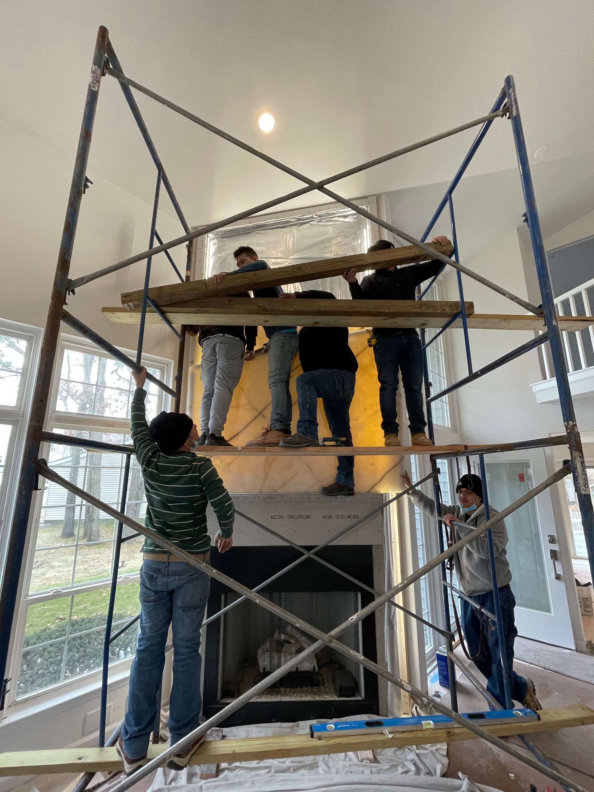 A group of people are working on a fireplace on a scaffolding.