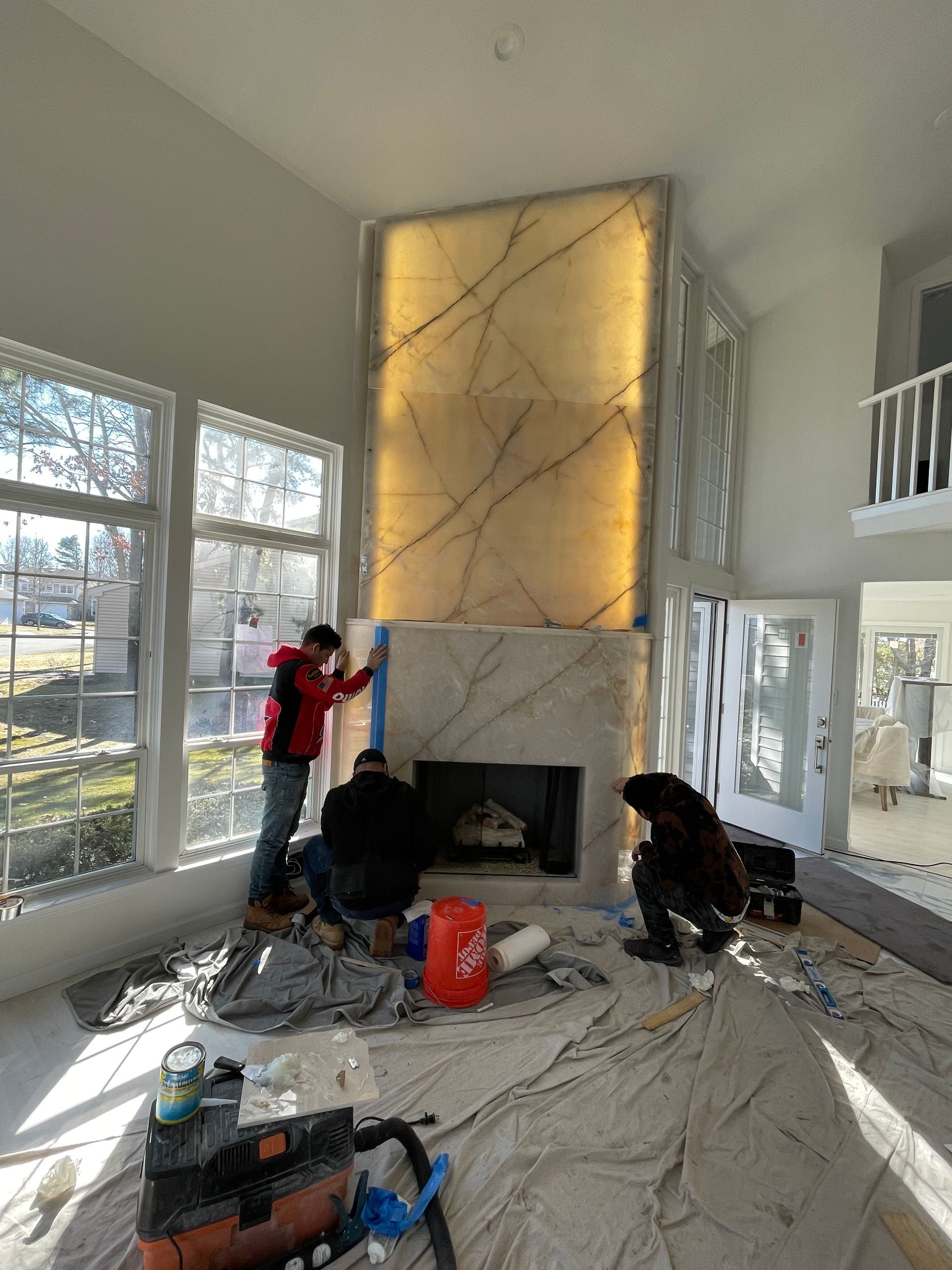 A group of men are working on a fireplace in a living room.