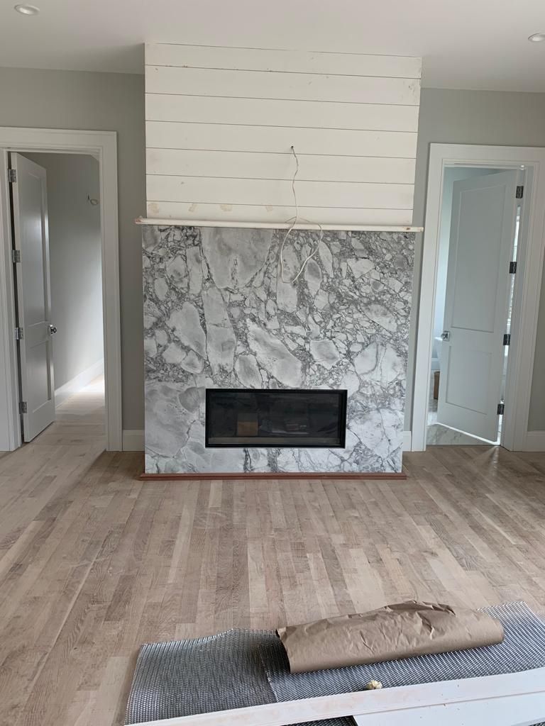 A living room with a marble fireplace and hardwood floors.