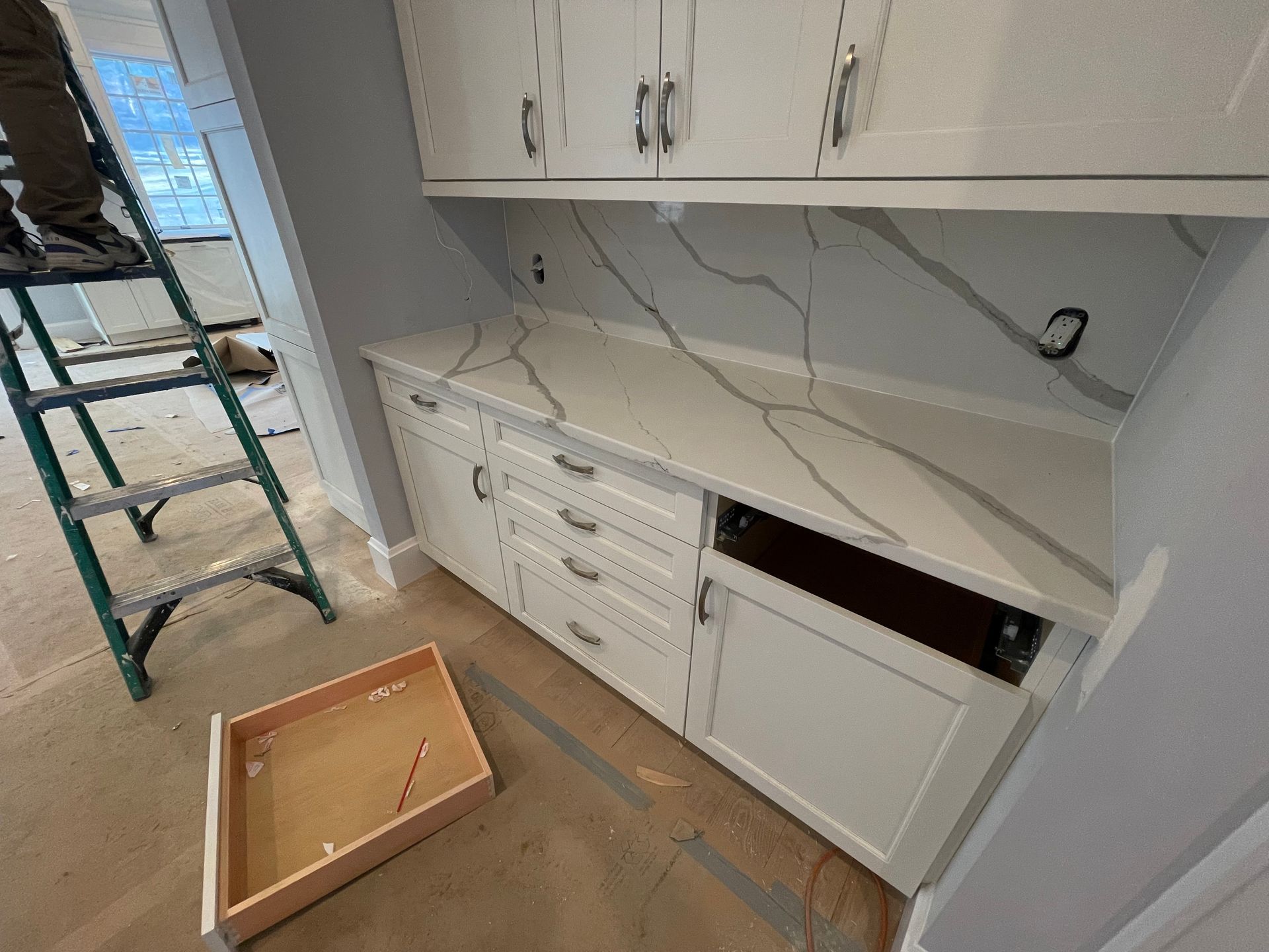 A person is standing on a ladder in a kitchen.