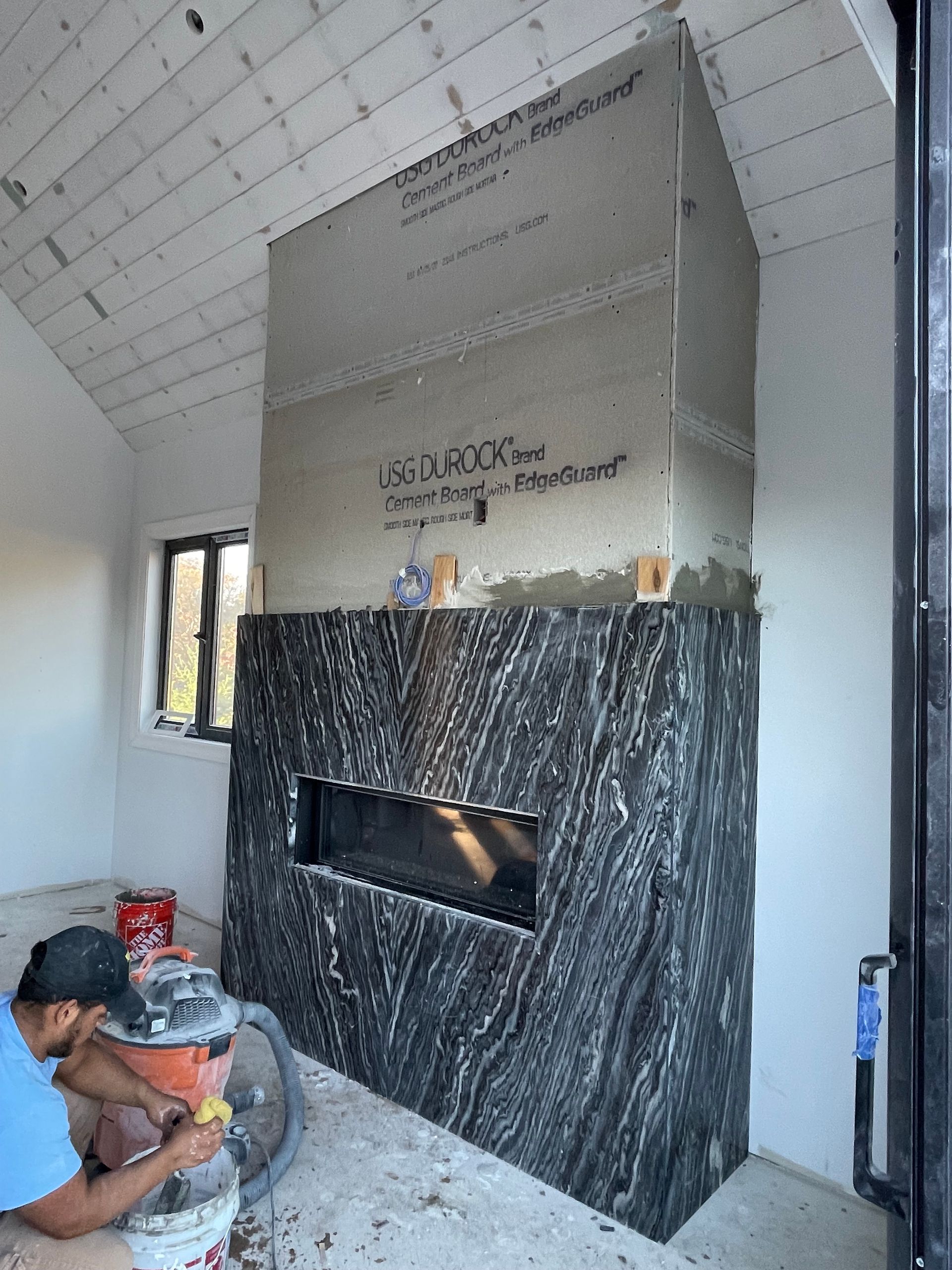 A man is working on a fireplace in a room.