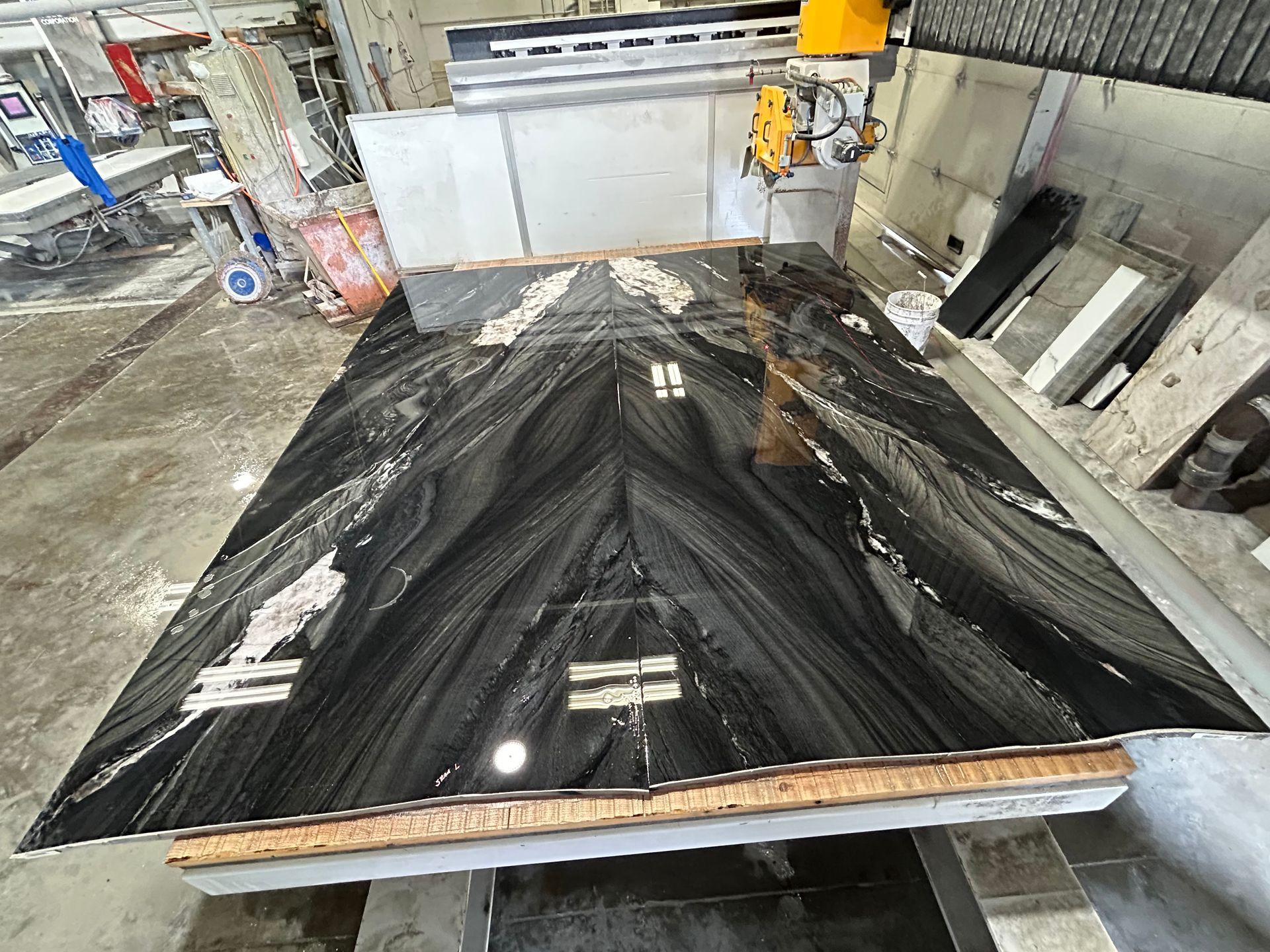 A large black marble slab is sitting on top of a table in a factory.
