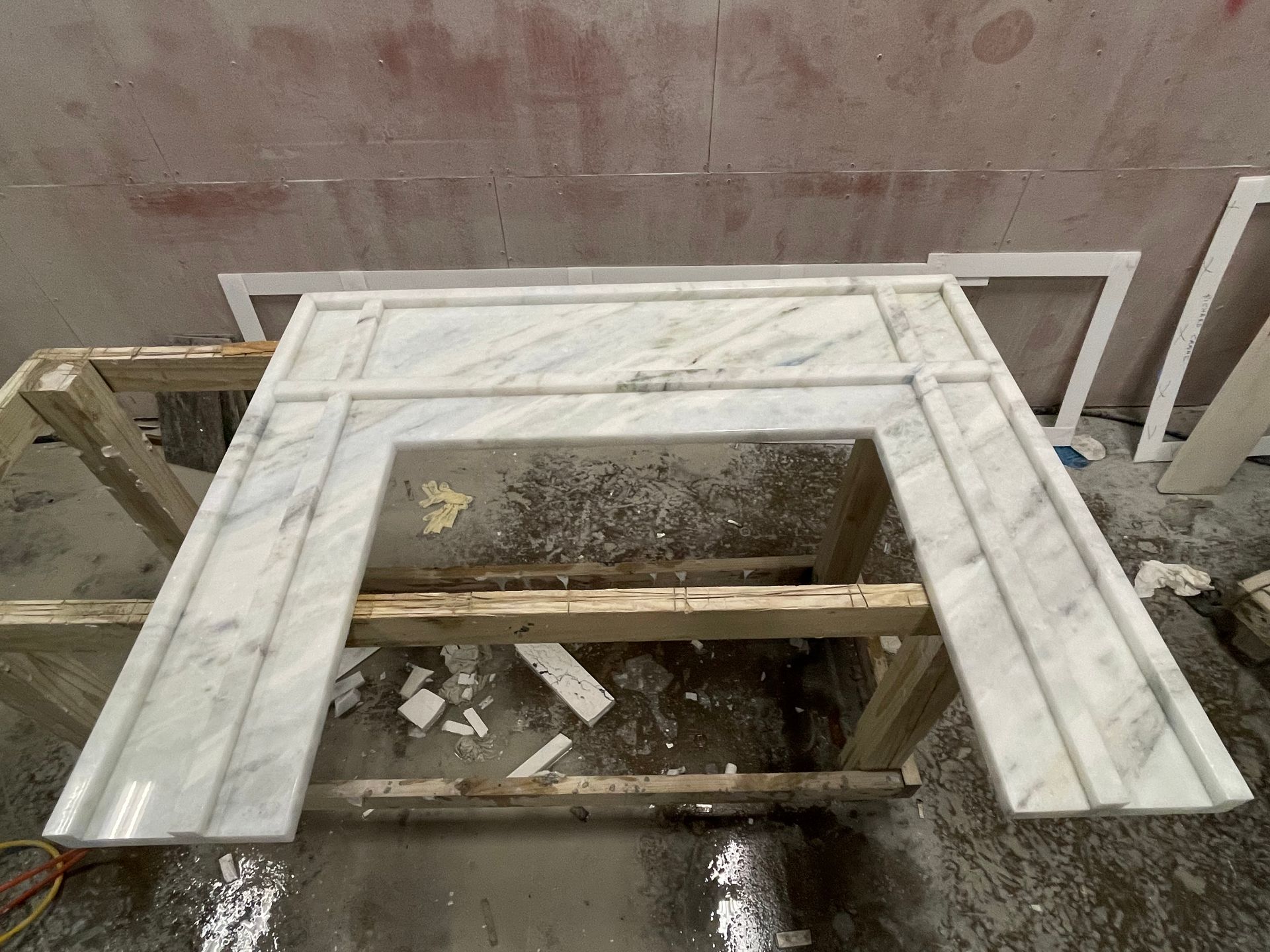 A white marble fireplace mantle is sitting on top of a wooden frame.
