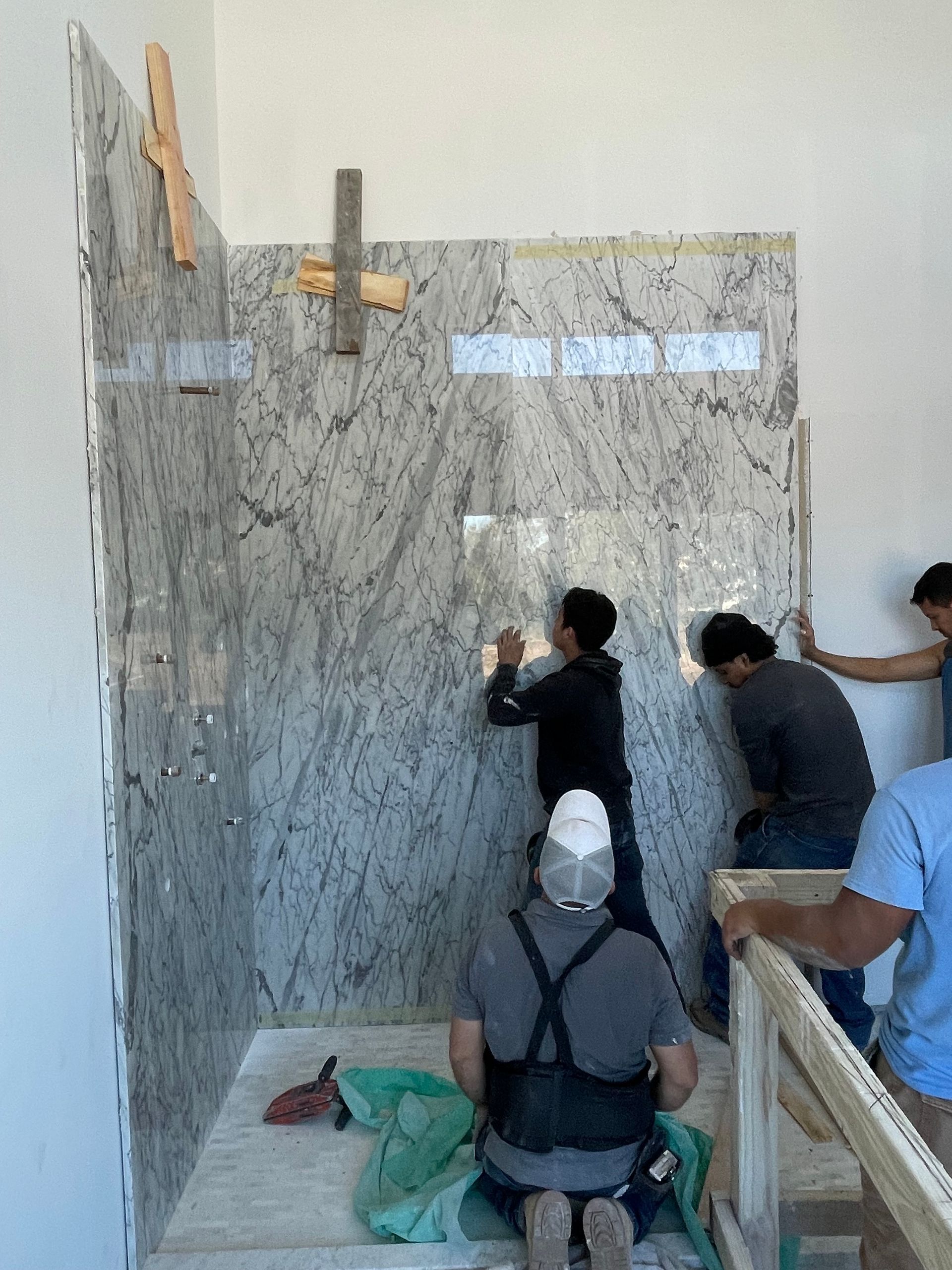 A group of people are working on a wall in a bathroom.