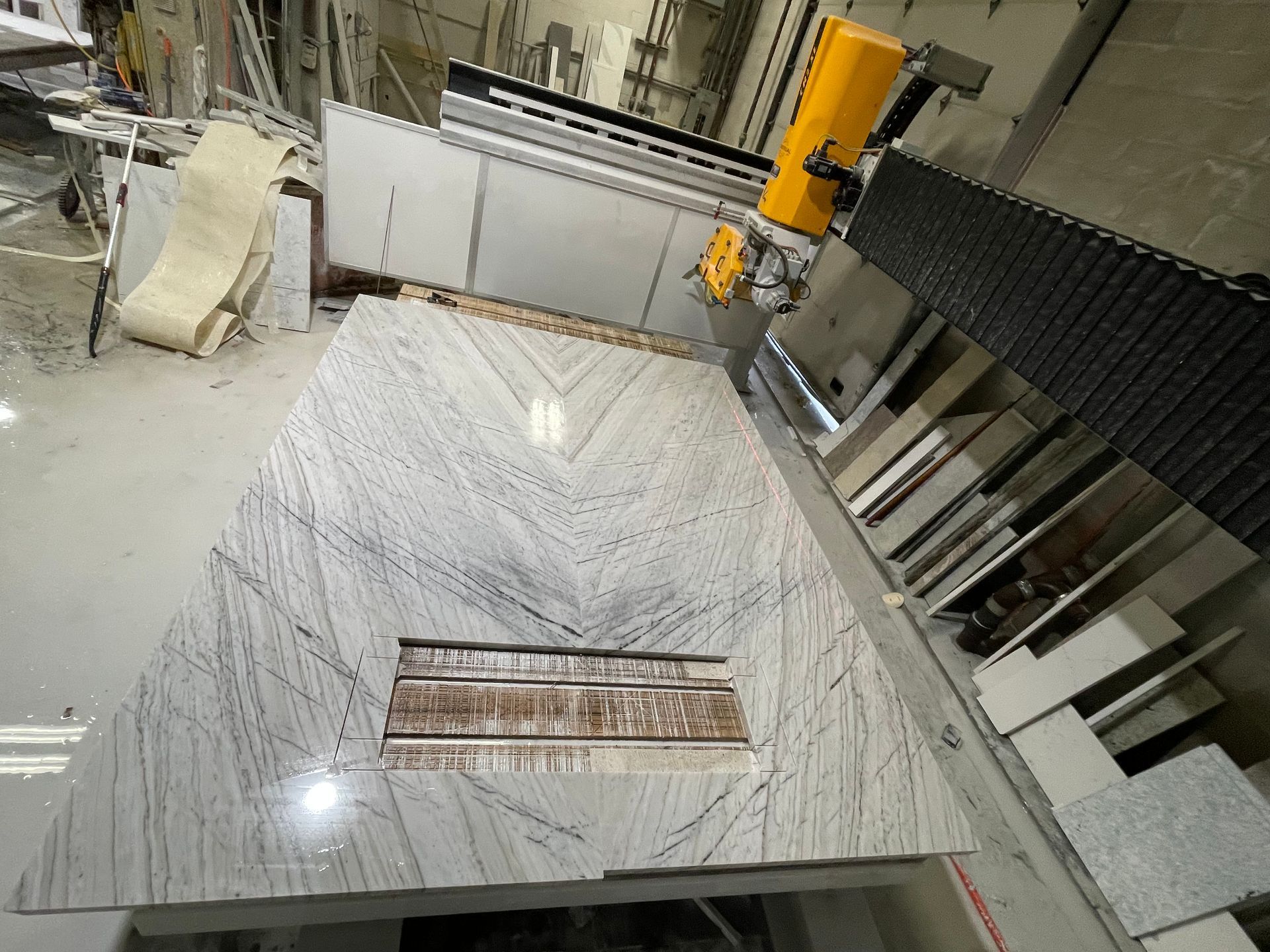 A marble countertop is being cut by a machine in a factory.
