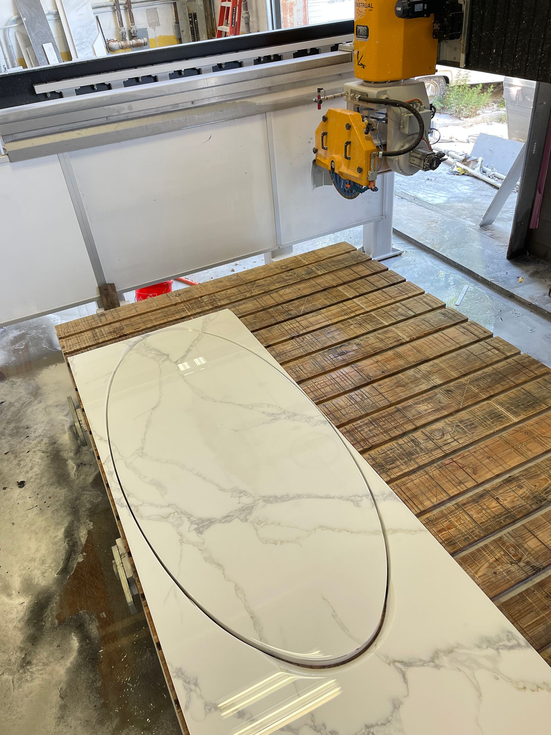 A machine is cutting a piece of marble on a wooden table.